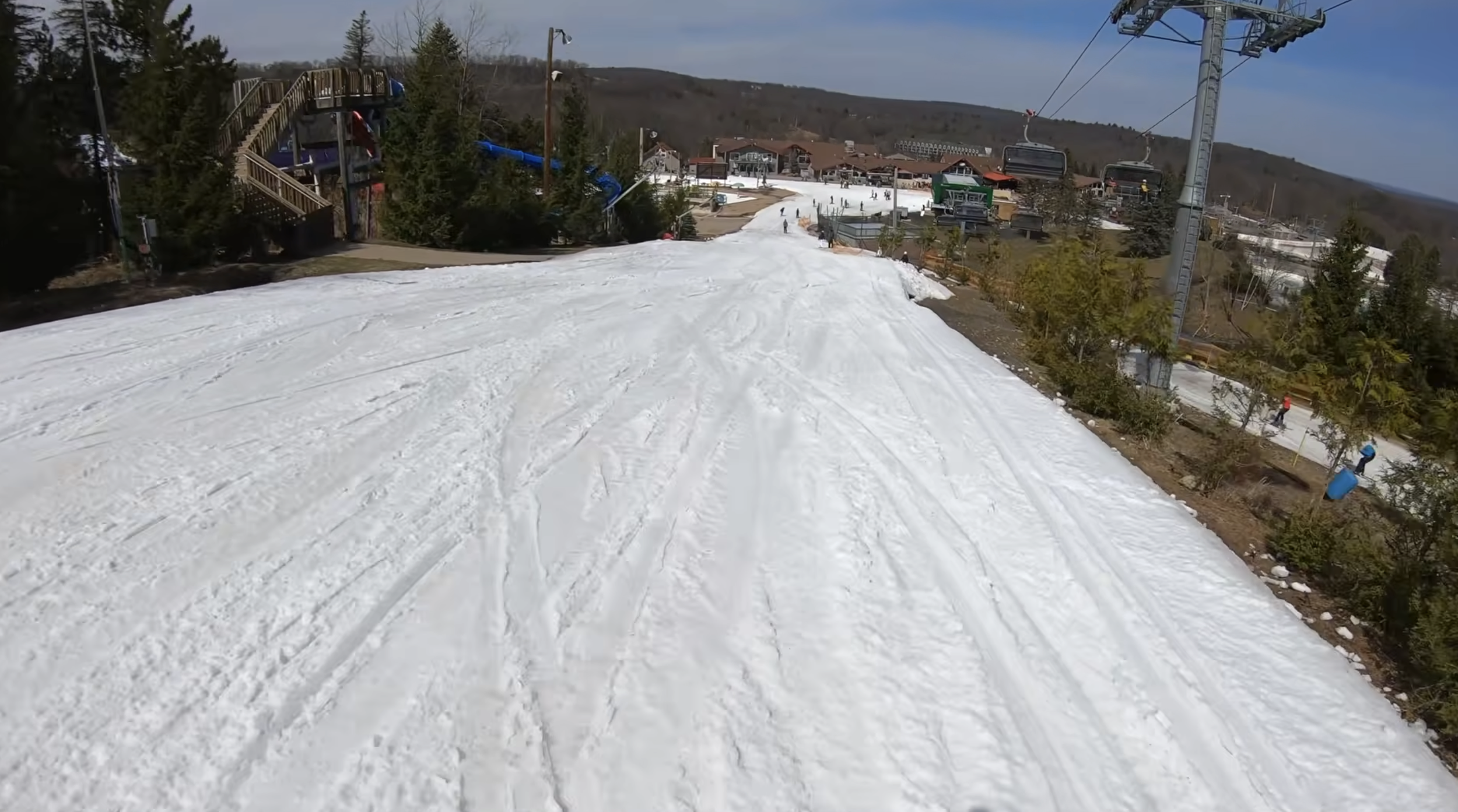 Skiing down a narrow slope at Camelback ski resort, Pennsylvania, with a bubble lift on one side and a waterslide on the other