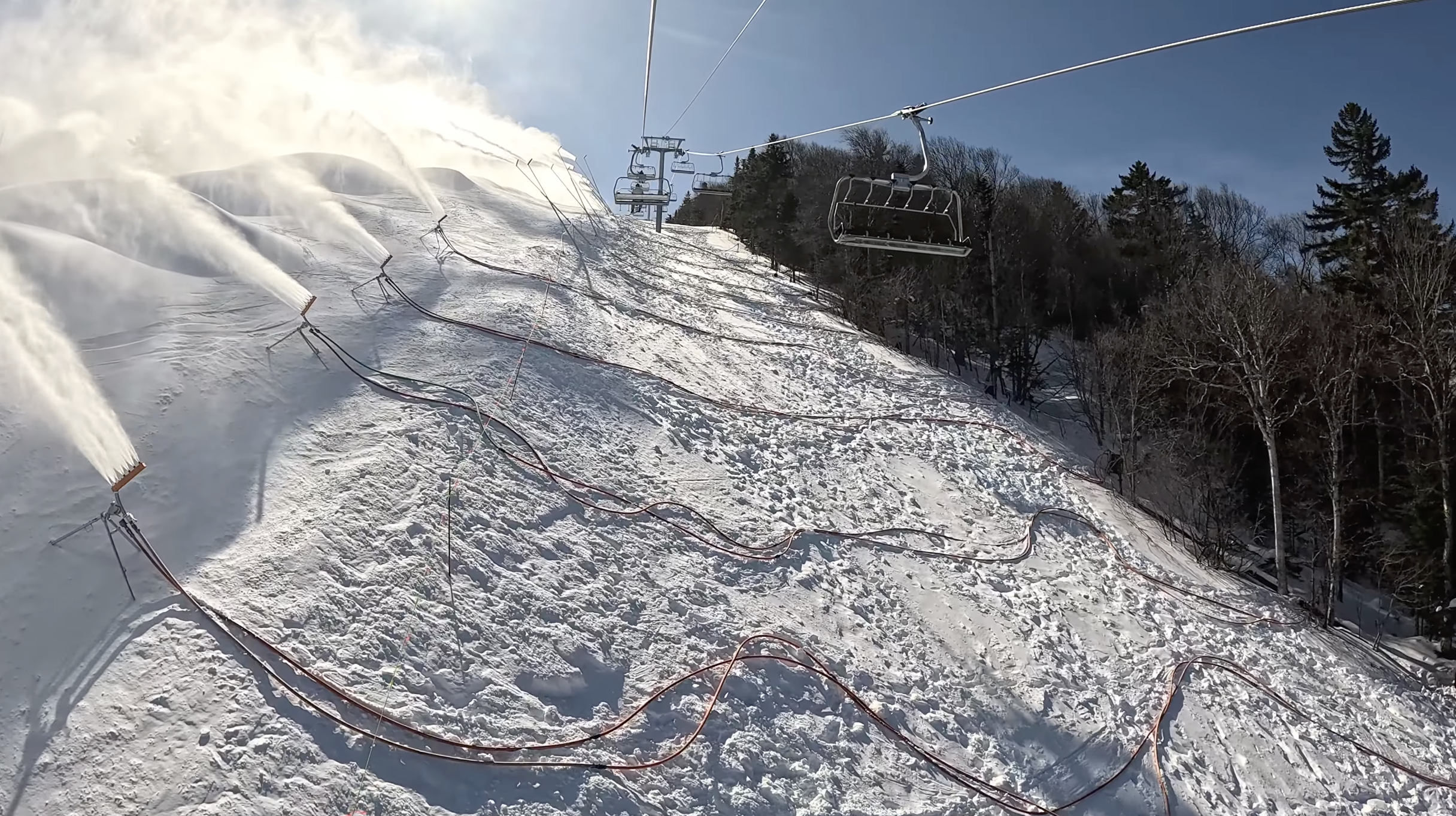 Riding up a six-seater chairlift above active snowmaking guns at Killington ski resort, Vermont