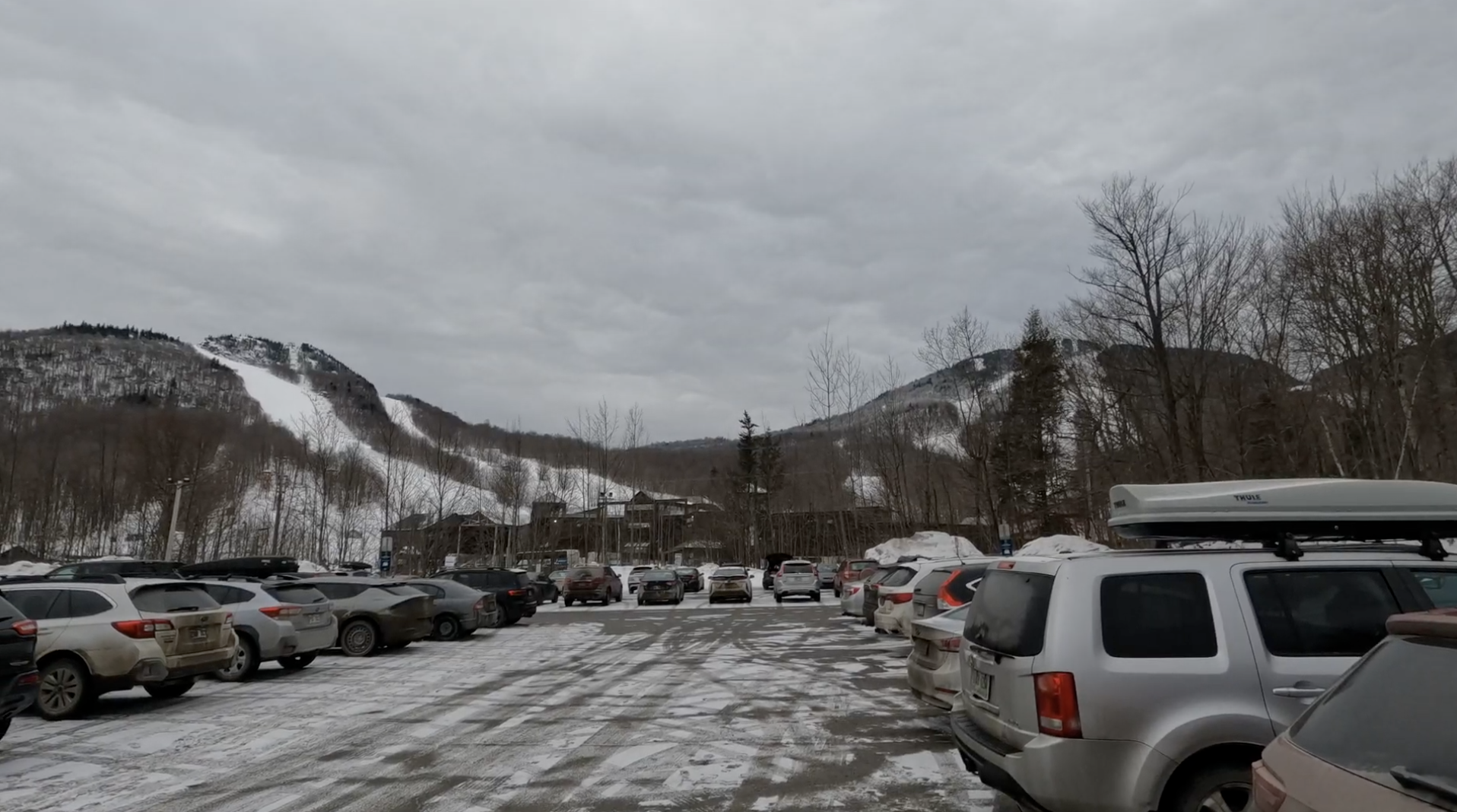Snowy parking lot with cars and ski hills in the background at Mont Orford, Quebec