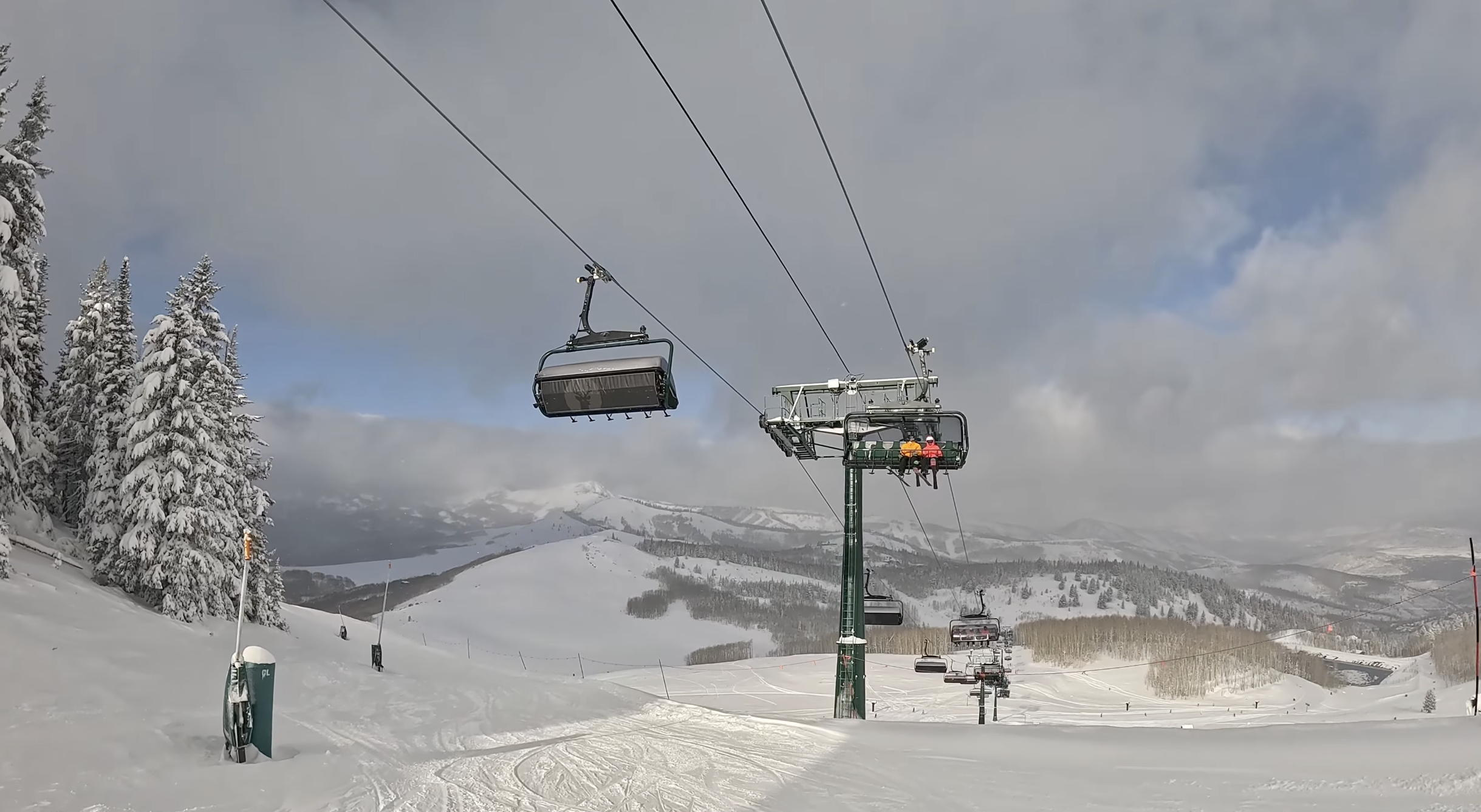 Skiers ride up a bubble chairlift on a cloudy day at Deer Valley ski resort, Utah