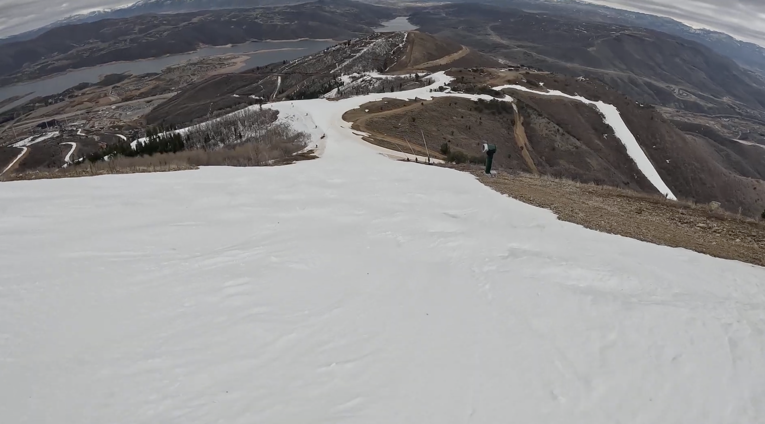 Skiing down a narrow ridge on a cloudy day, with brown dirt mountains and white strips of snow at Deer Valley ski resort, Utah