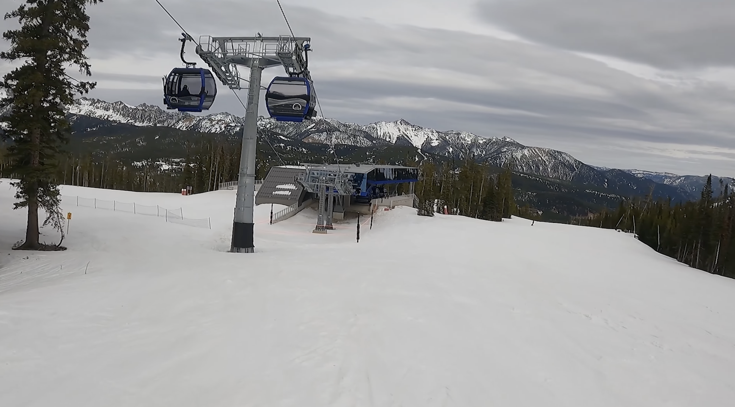 Gondola cabins climb out of a modern glass station at Big Sky resort, Montana