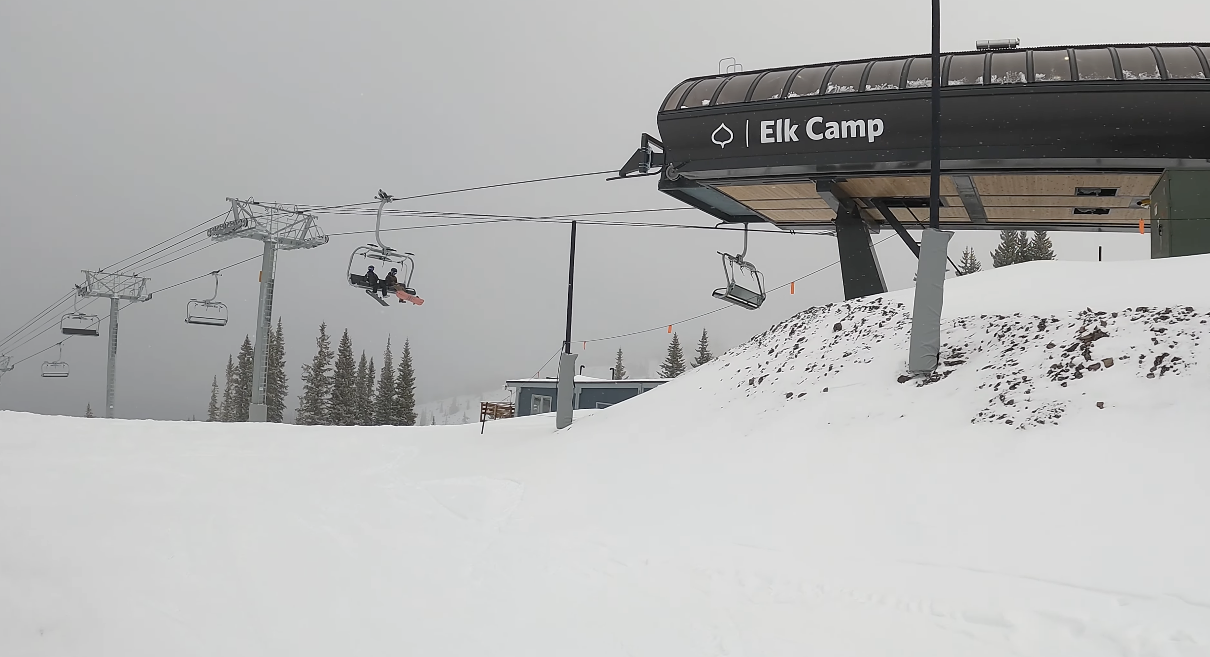 Snowboarders ride up the Elk Camp chairlift on a snowy day at Aspen Snowmass, Colorado