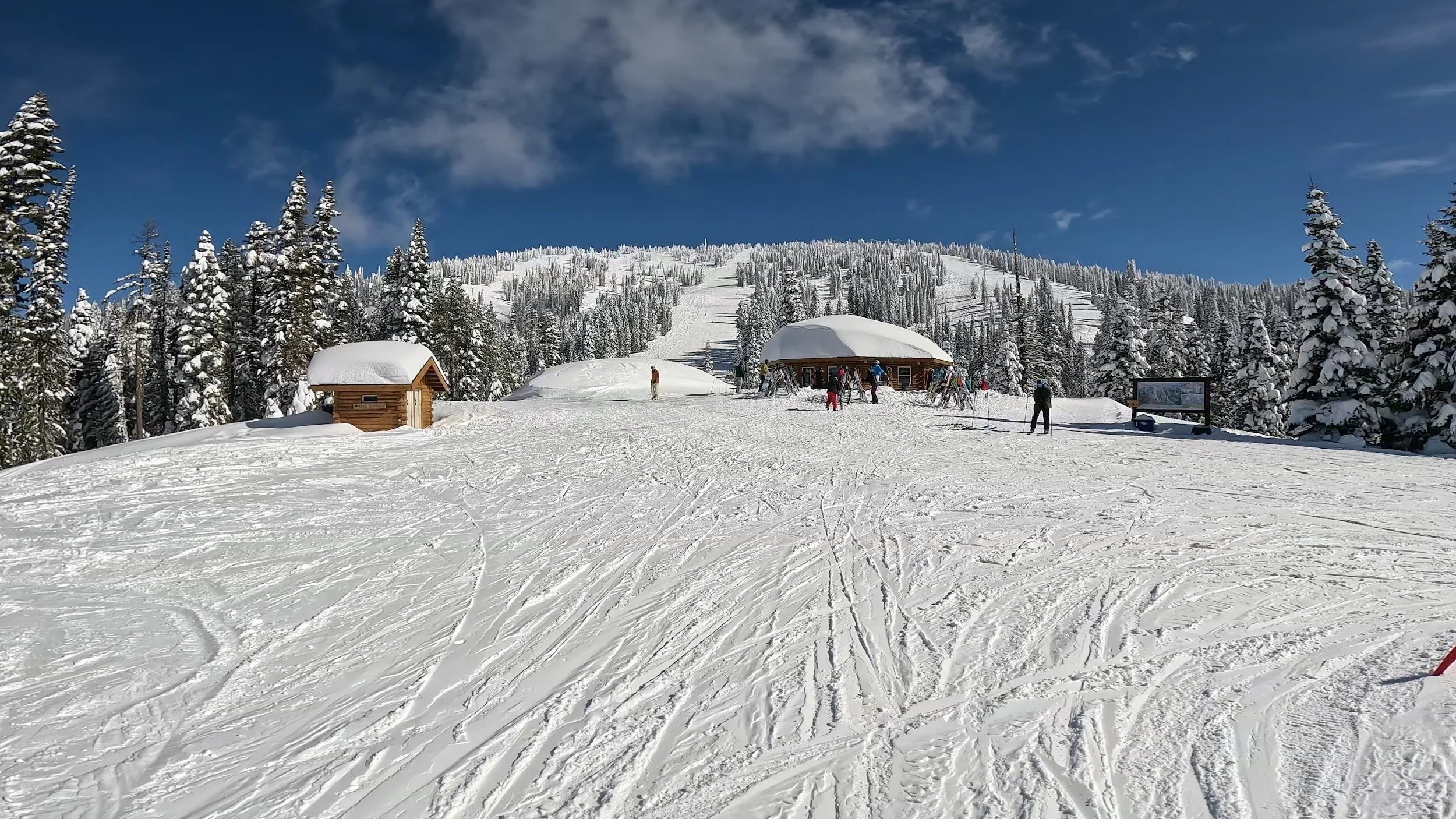 View up Brundage's front side from near the base, with small lodges and snow-covered trees