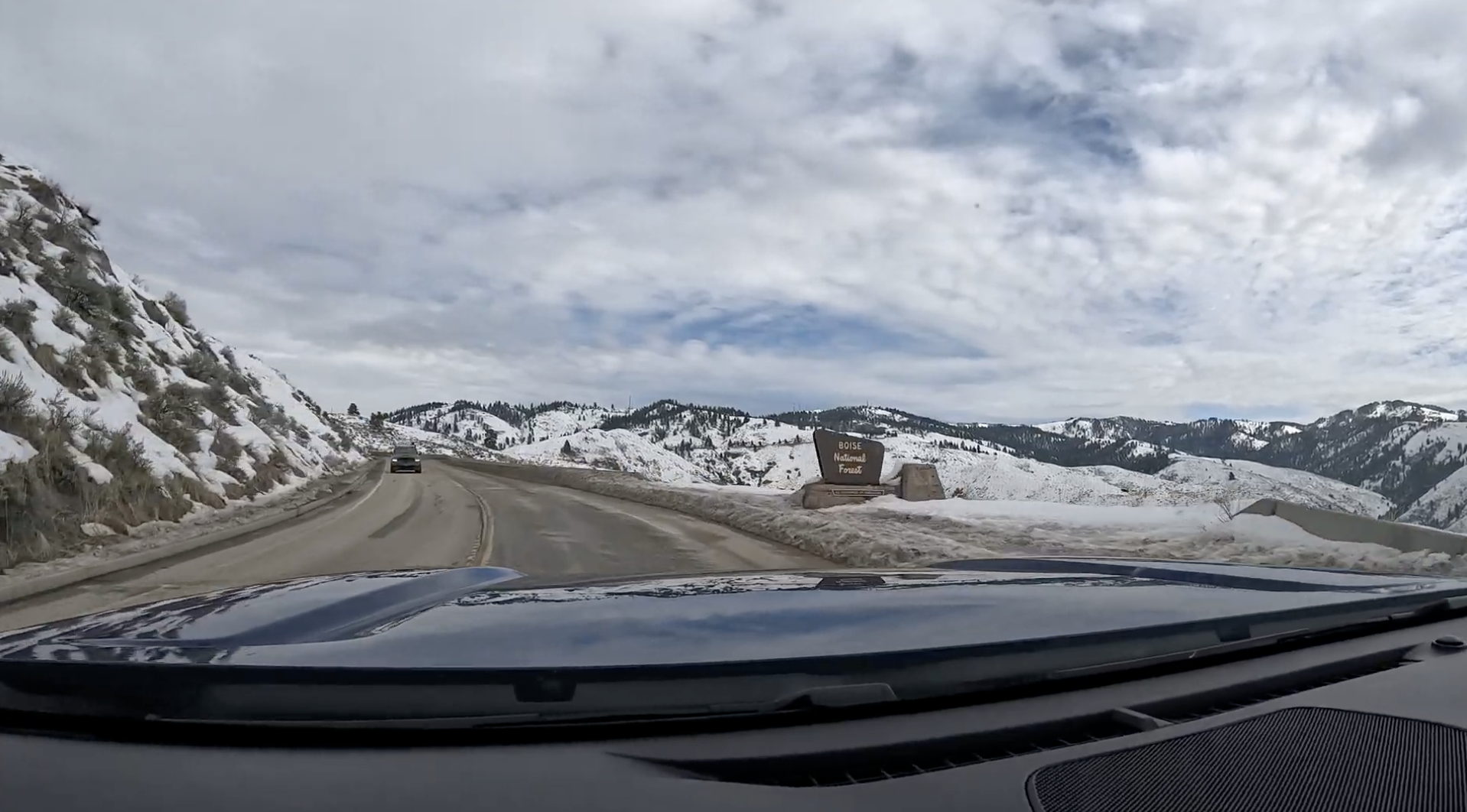 POV of driving up a snowy mountain road with a sign for Boise National Forest in Idaho