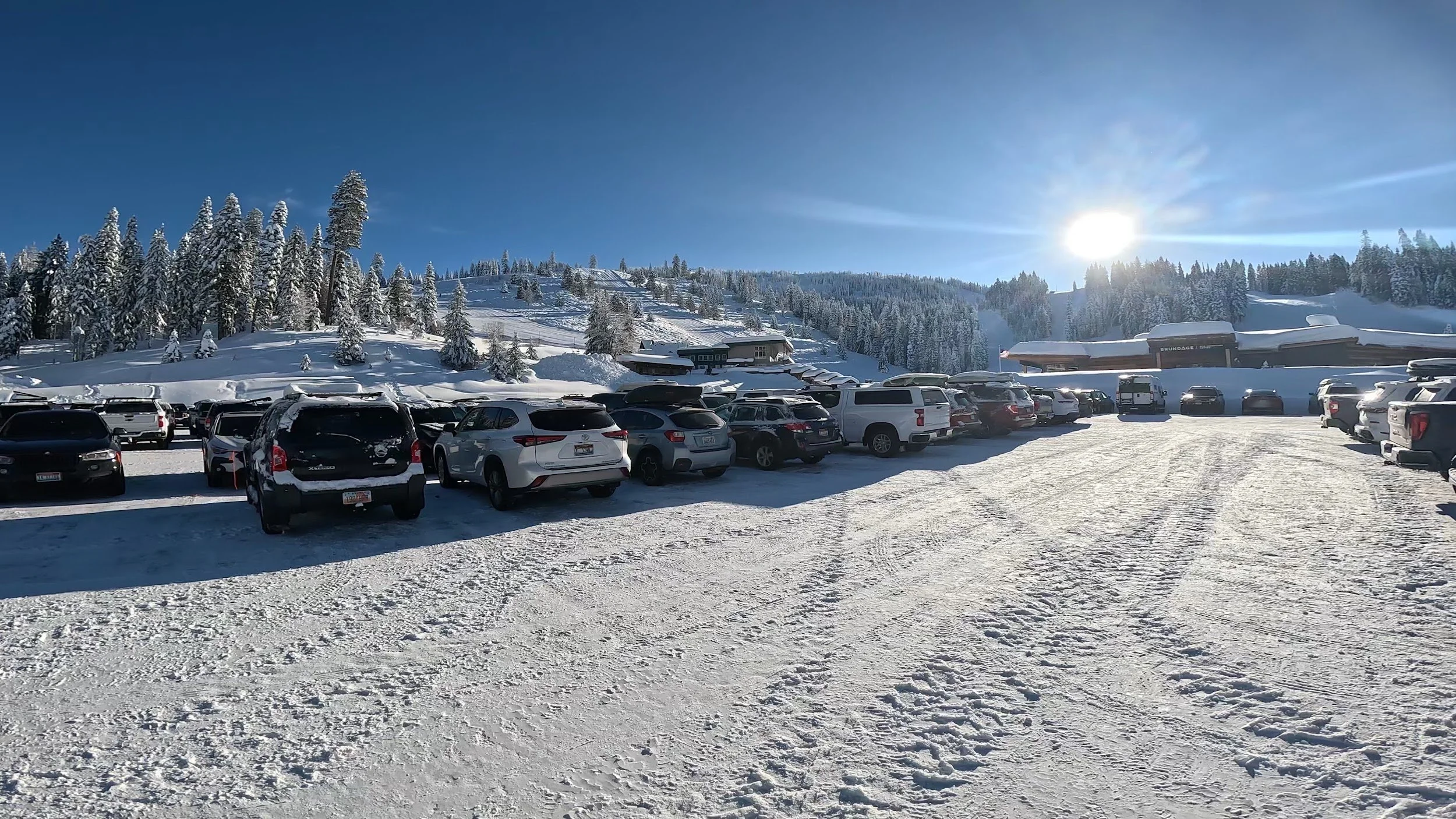 Parking lot at the base of Brundage Mountain lined with snow-covered trees