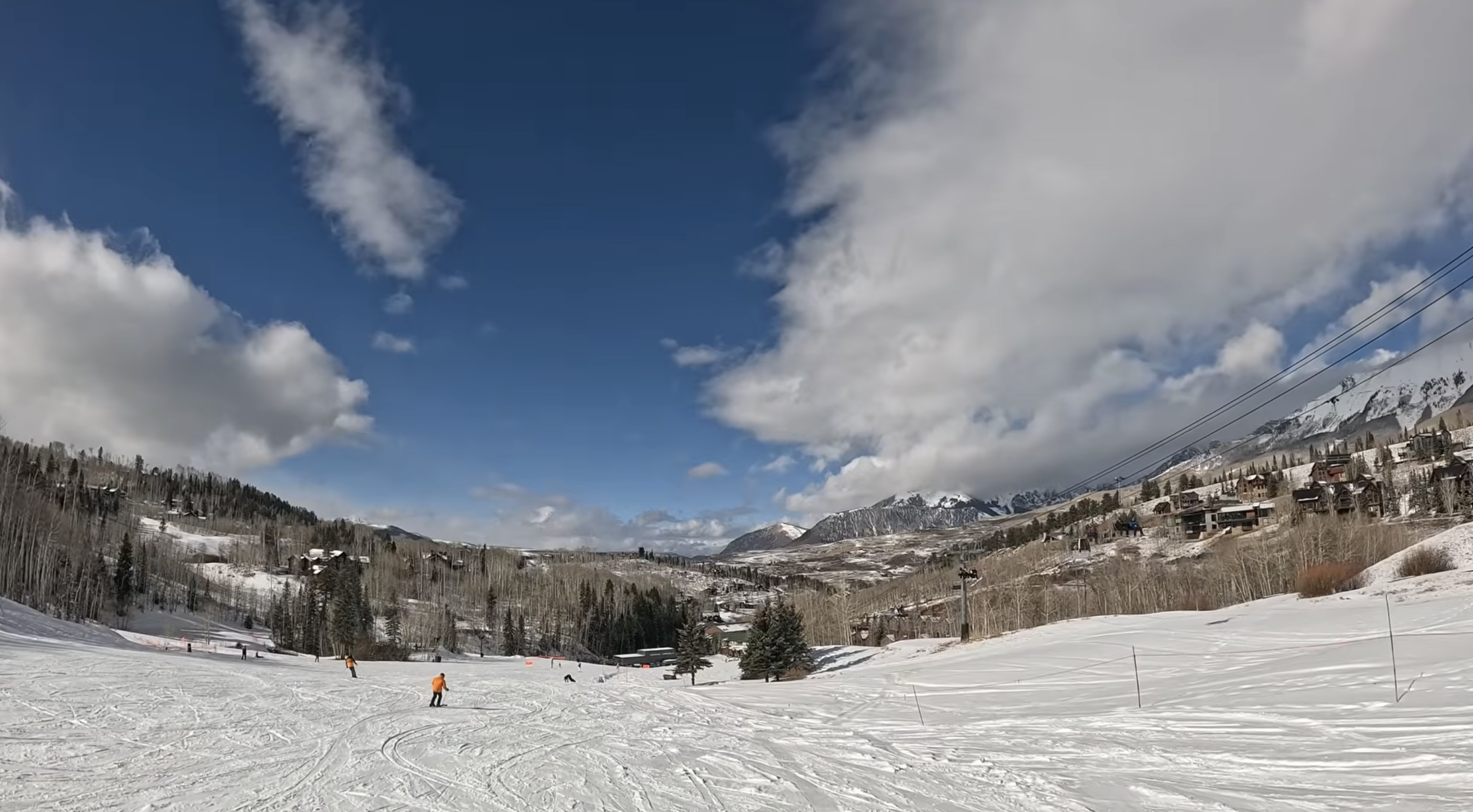 A wide open ski slope on a sunny day with condos in the background at Telluride ski resort, Colorado