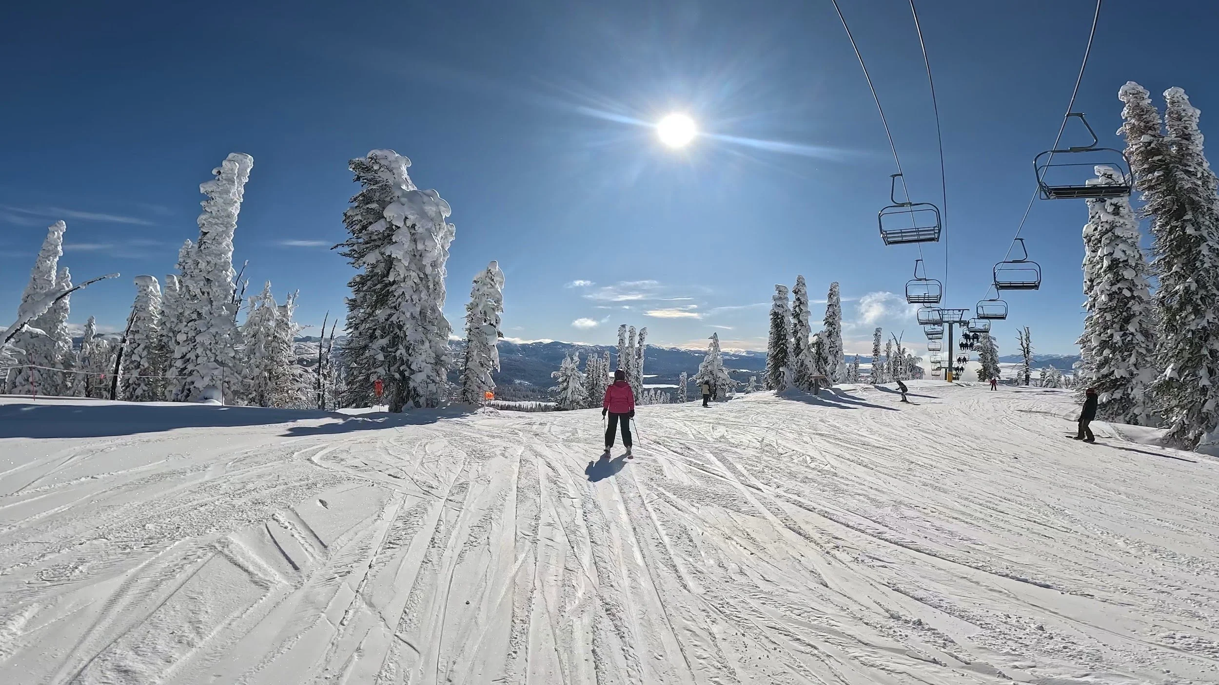 Skier descending a groomed run in Brundage's Lakeview pod, with frosted trees and a chairlift
