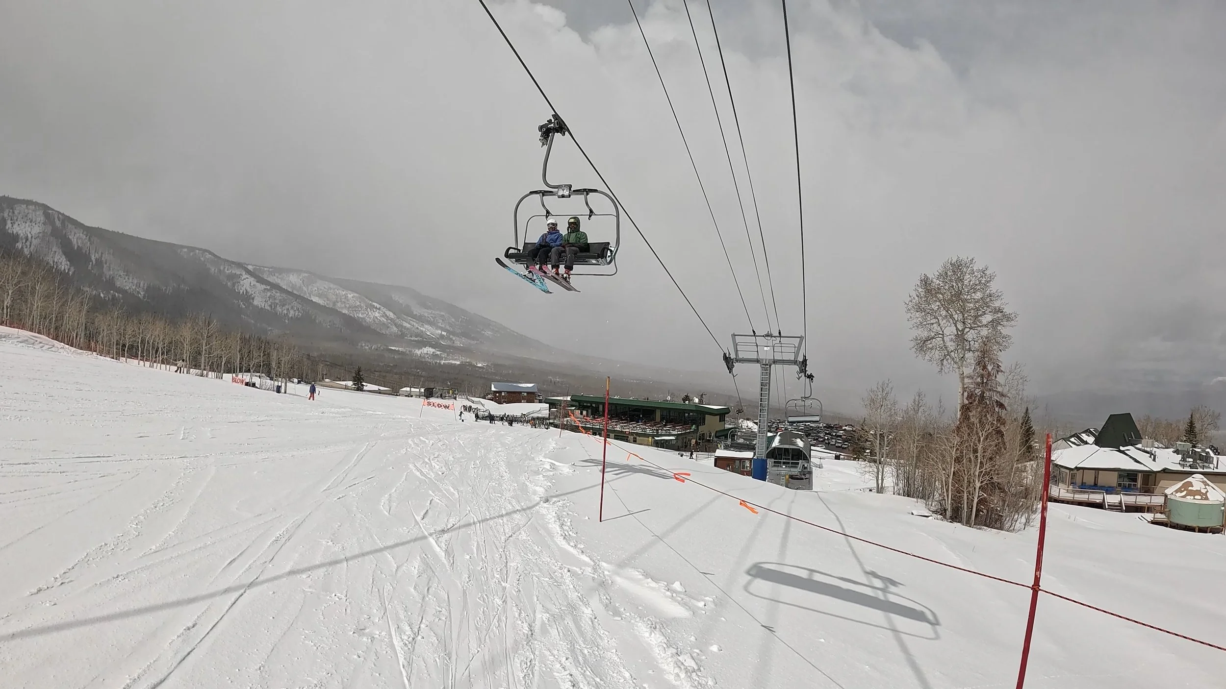 A view of a chairlift at Powderhorn ski resort, with the base area in the background.