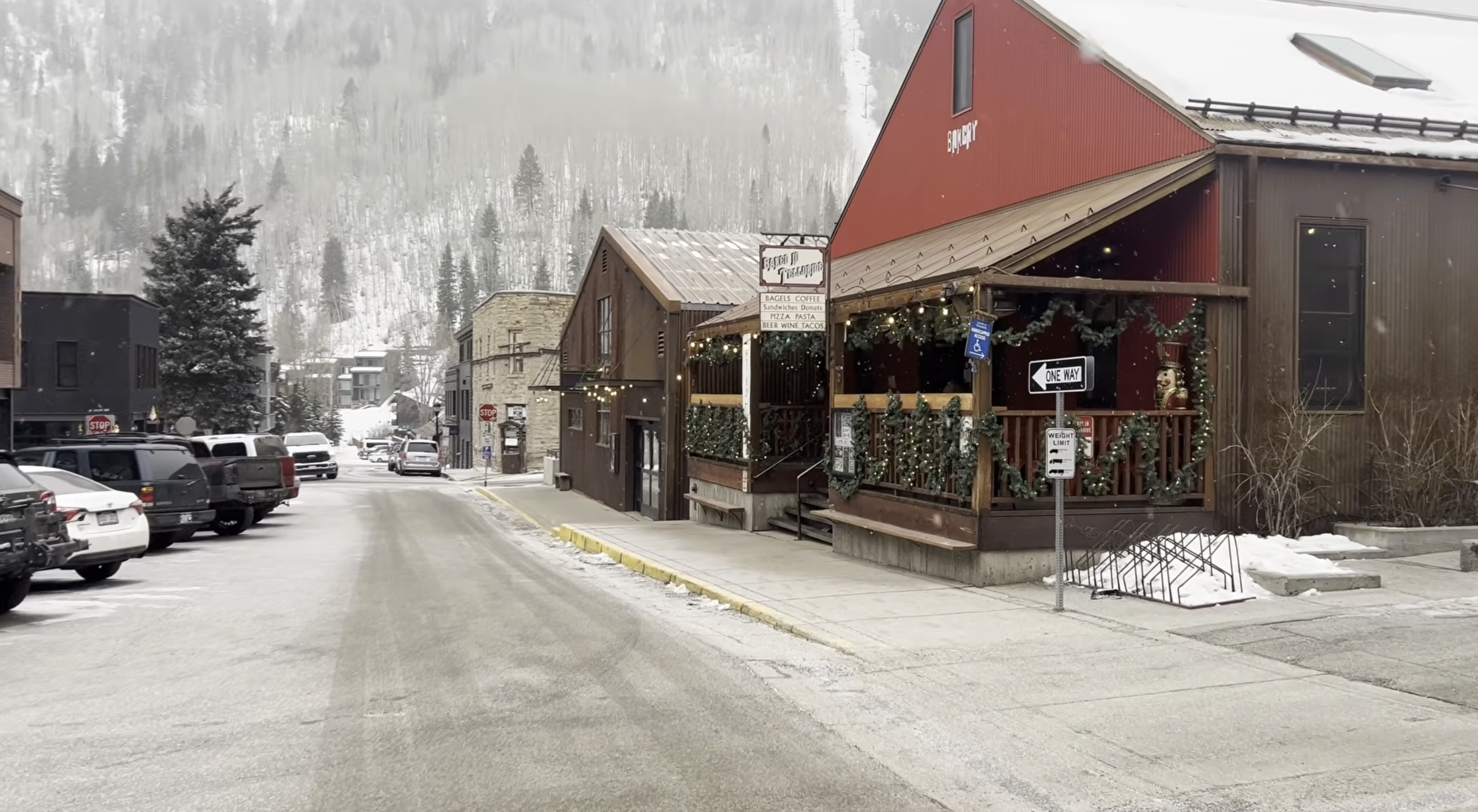 Snowy town street in Telluride, Colorado with a bakery and other wooden and stone buildings