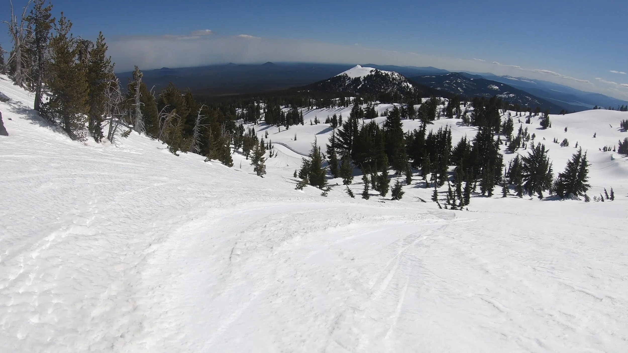 Looking down a snowy basin with some trees on a bluebird day at Mount Bachelor, Oregon