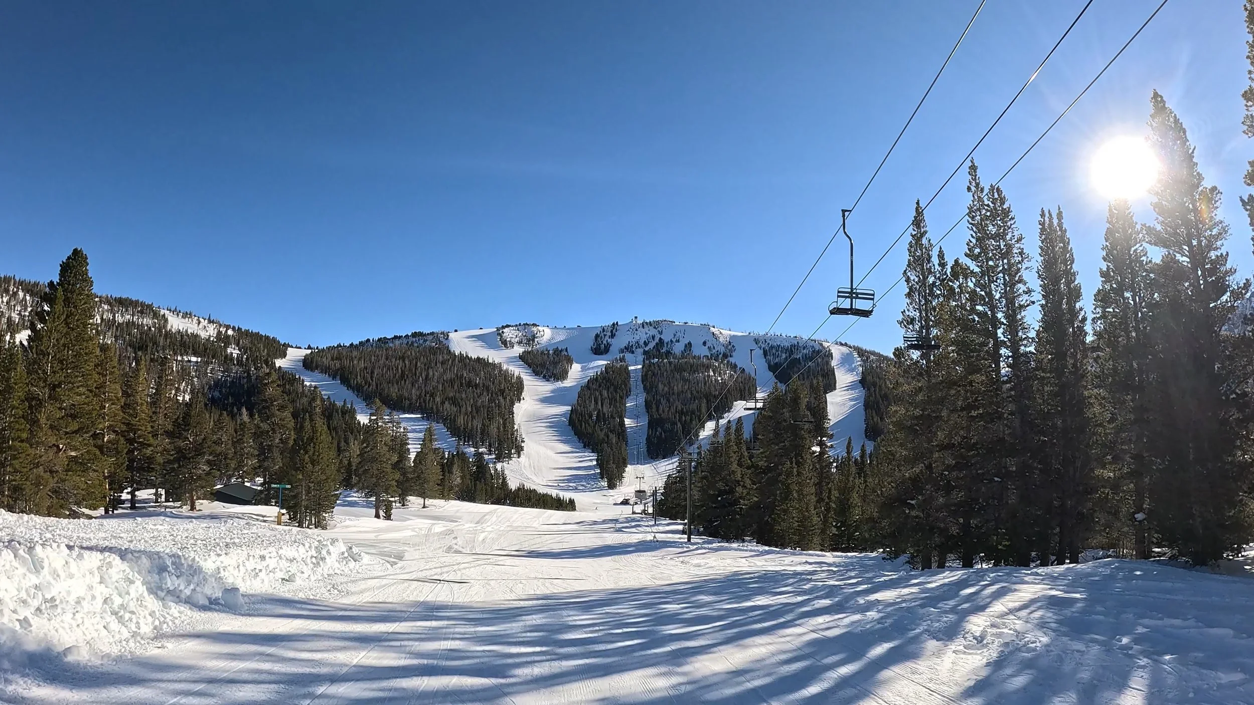 A view of tree-cut ski trails with a chairlift in the background at June Mountain.