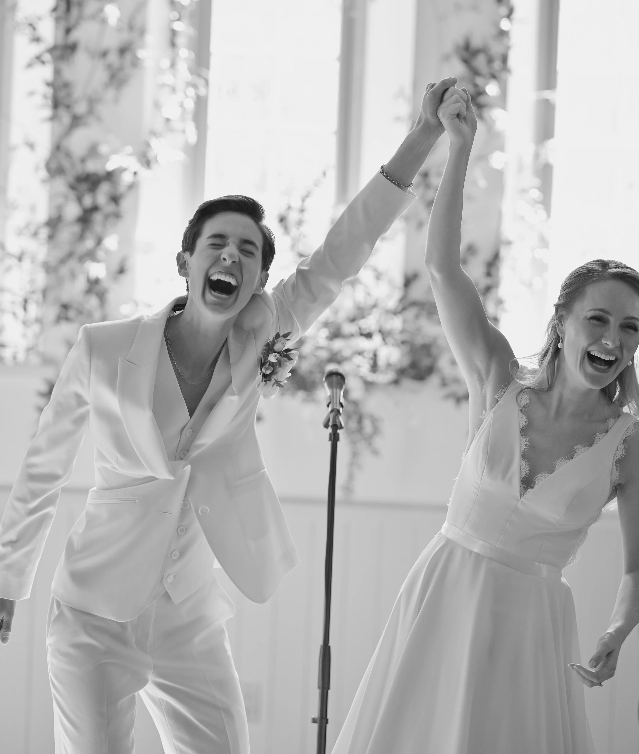 A happy couple celebrating their wedding, holding hands in the air and laughing, at Enoch Turner Schoolhouse Museum and Special Events Venue.