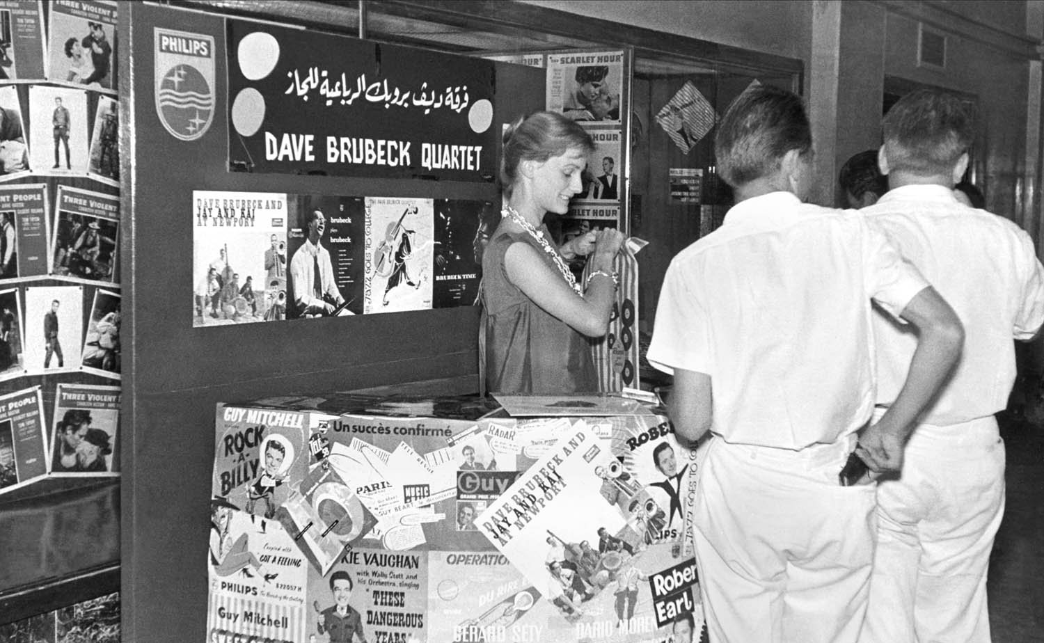 Dave Brubeck (obscured) signs autographs for fans in a record store. Baghdad, Iraq, 1958. Courtesy of the Brubeck Collection, Holt-Atherton Special Collections, University of the Pacific Library. Copyright Dave Brubeck.