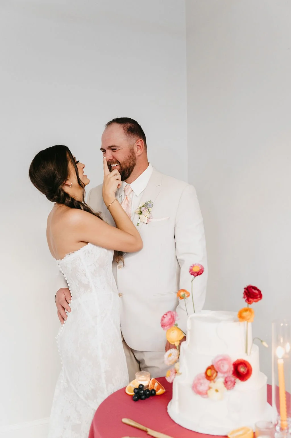 bride in white dress smudging cake on the groom's nose