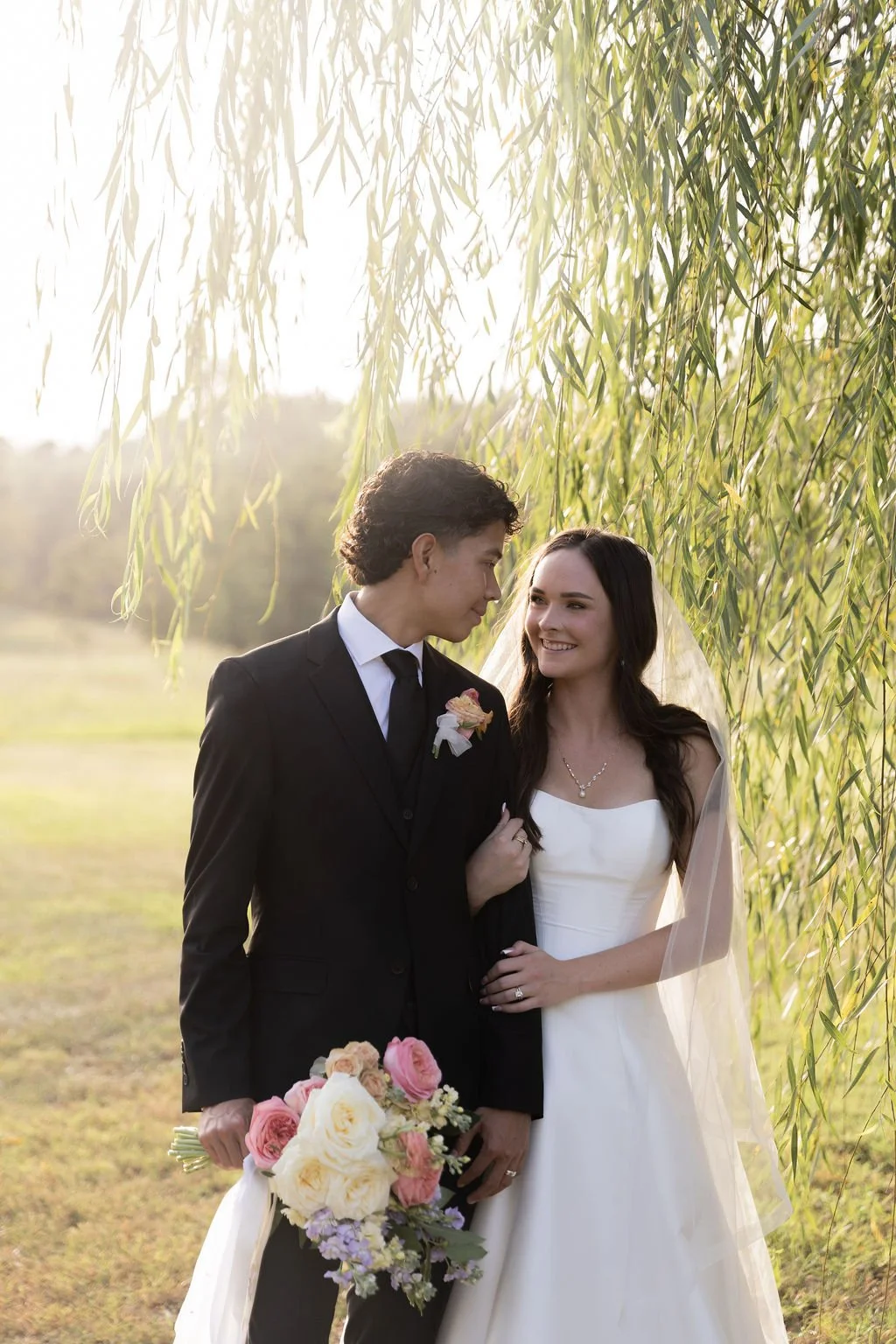 bride and groom standing in the willow trees at sunset oaks