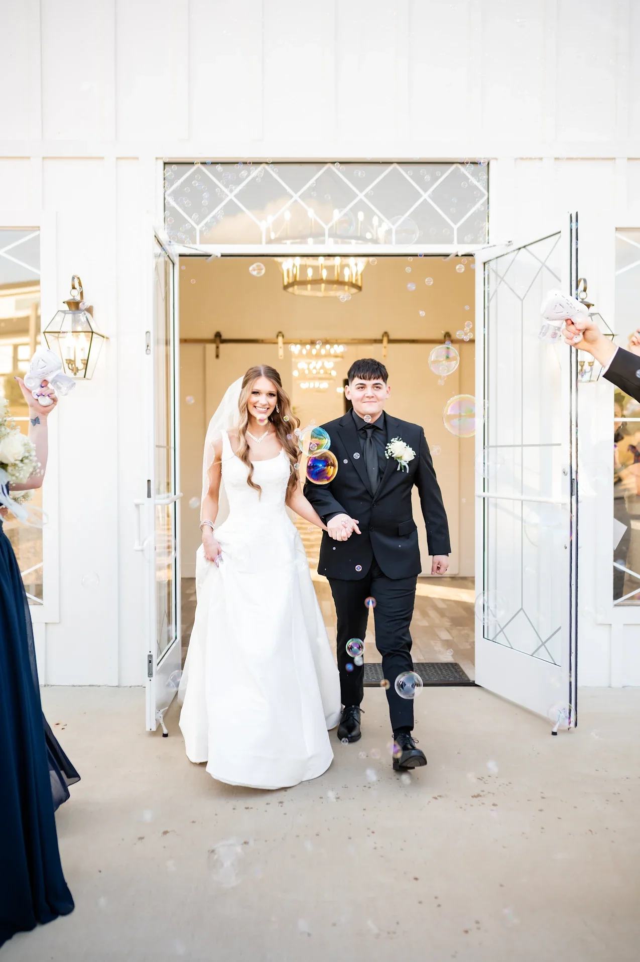 bride and groom walking outside the wedding venue as they blow bubbles