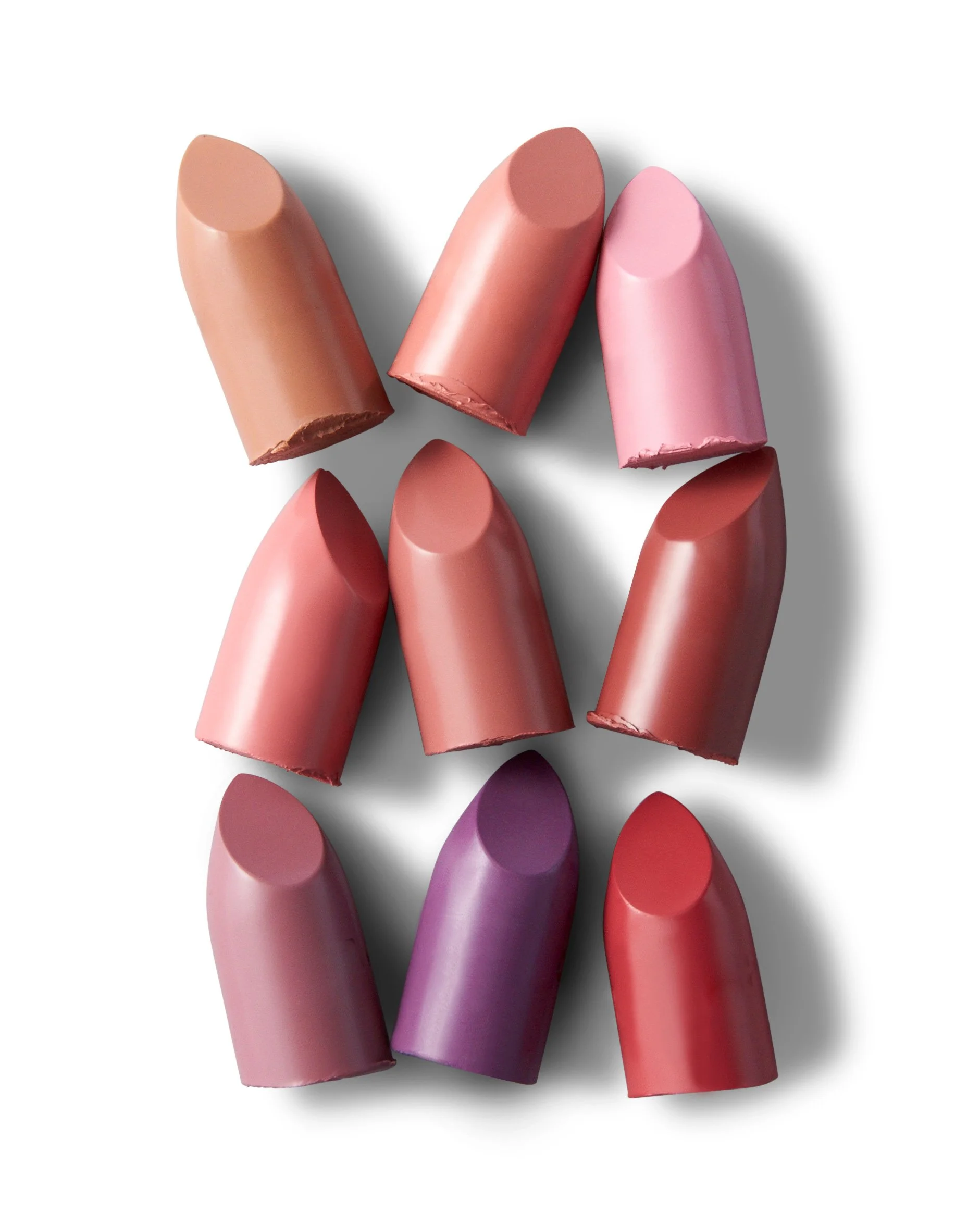 A collection of lipsticks in various shades of pink, purple, and red, arranged on a white background. Beaty Product Photography Los Angeles.