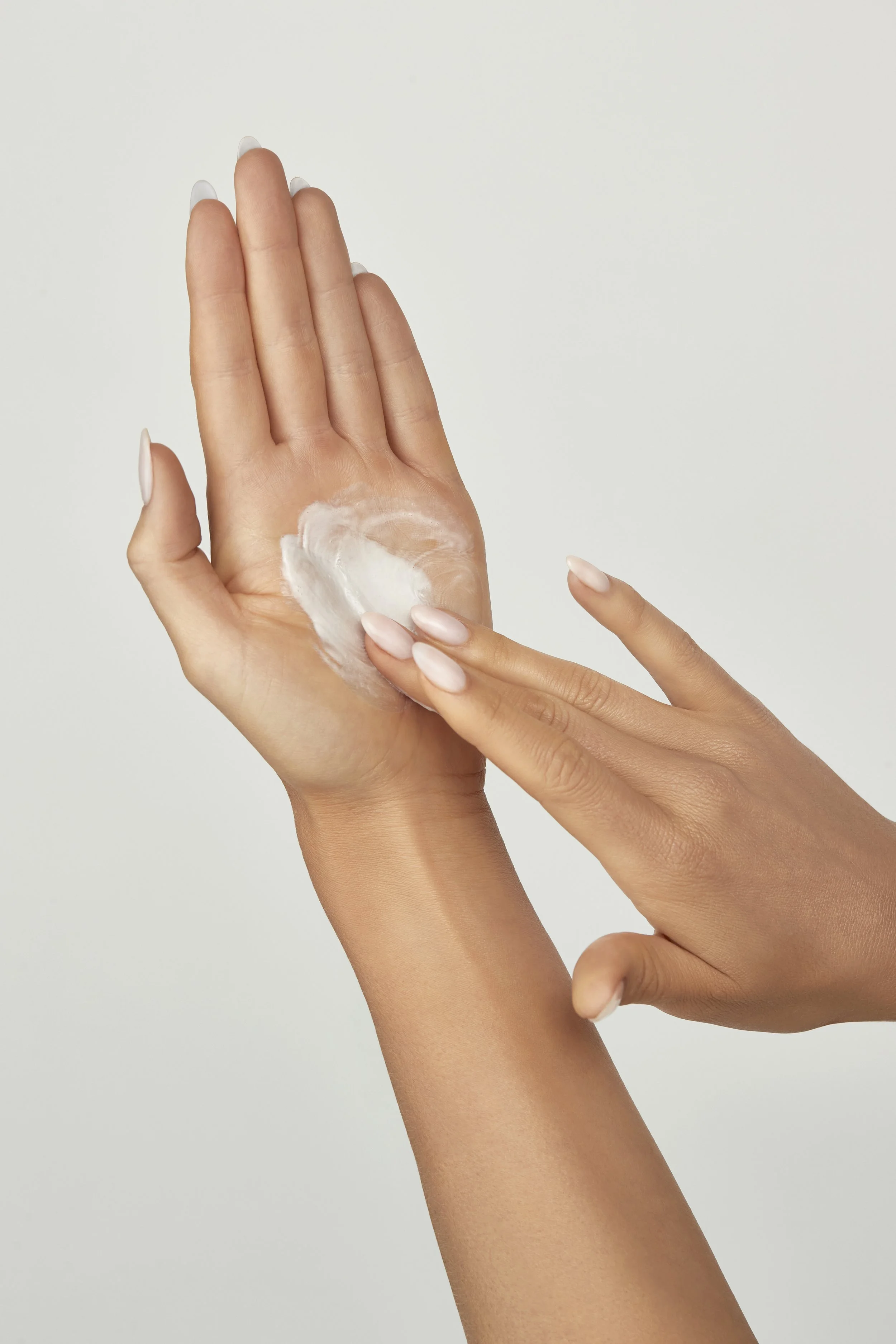 A person applying white lotion or cream to their hand. Beaty Product Photography Los Angeles.
