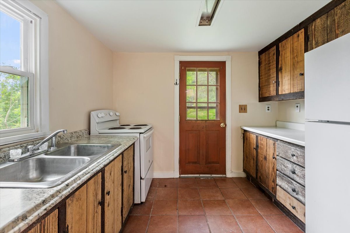 Apartment kitchen with fridge, large double sink, stove/oven.