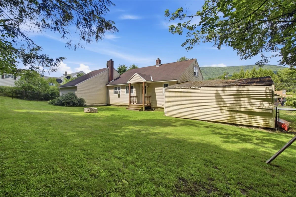 Image of the back of a house from far corner of backyard. The yard includes a firepit.