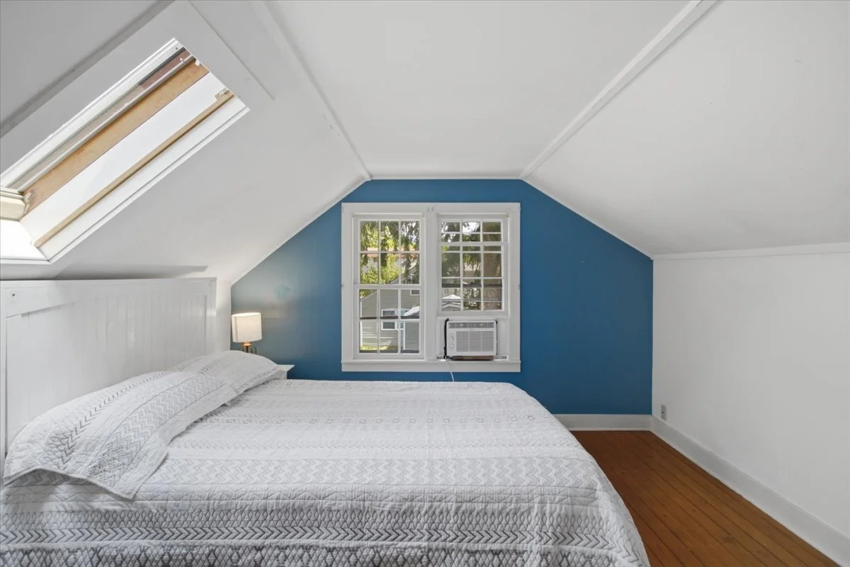 Upstairs bedroom with slanted skylights over bed.