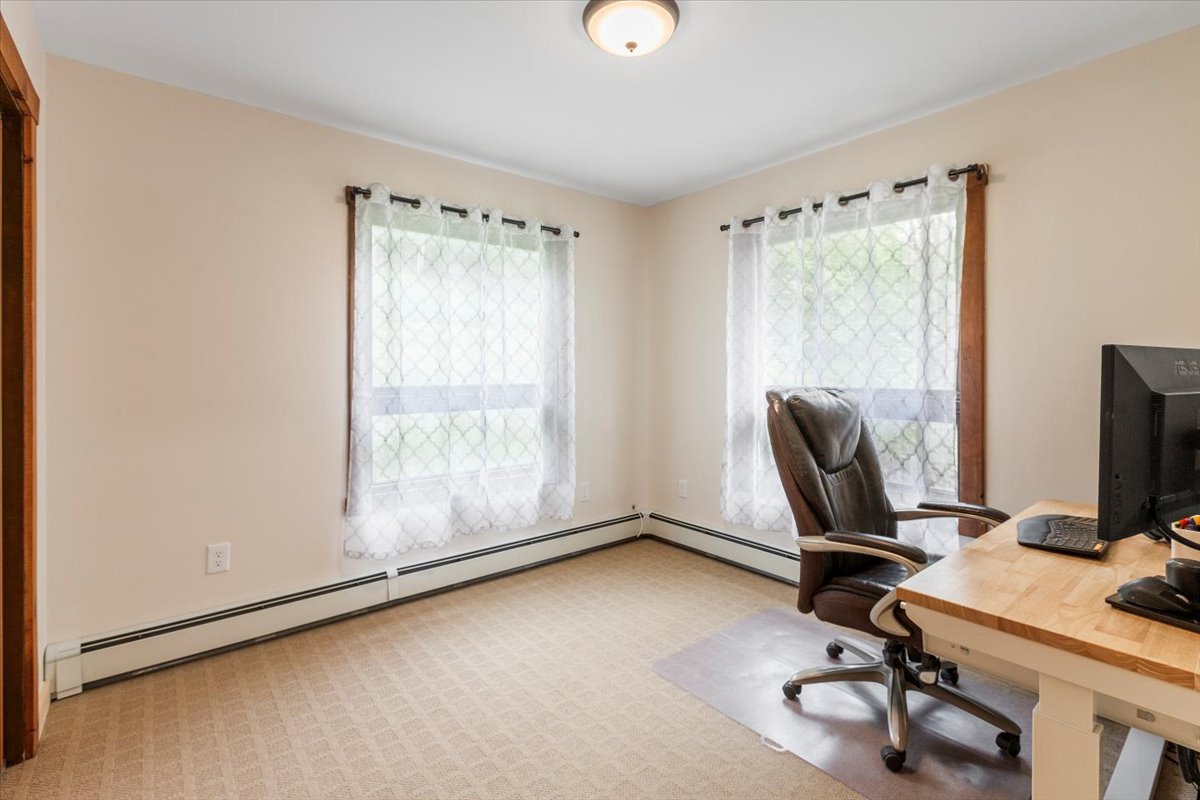 Carpeted office with huge windows and overhead lighting.
