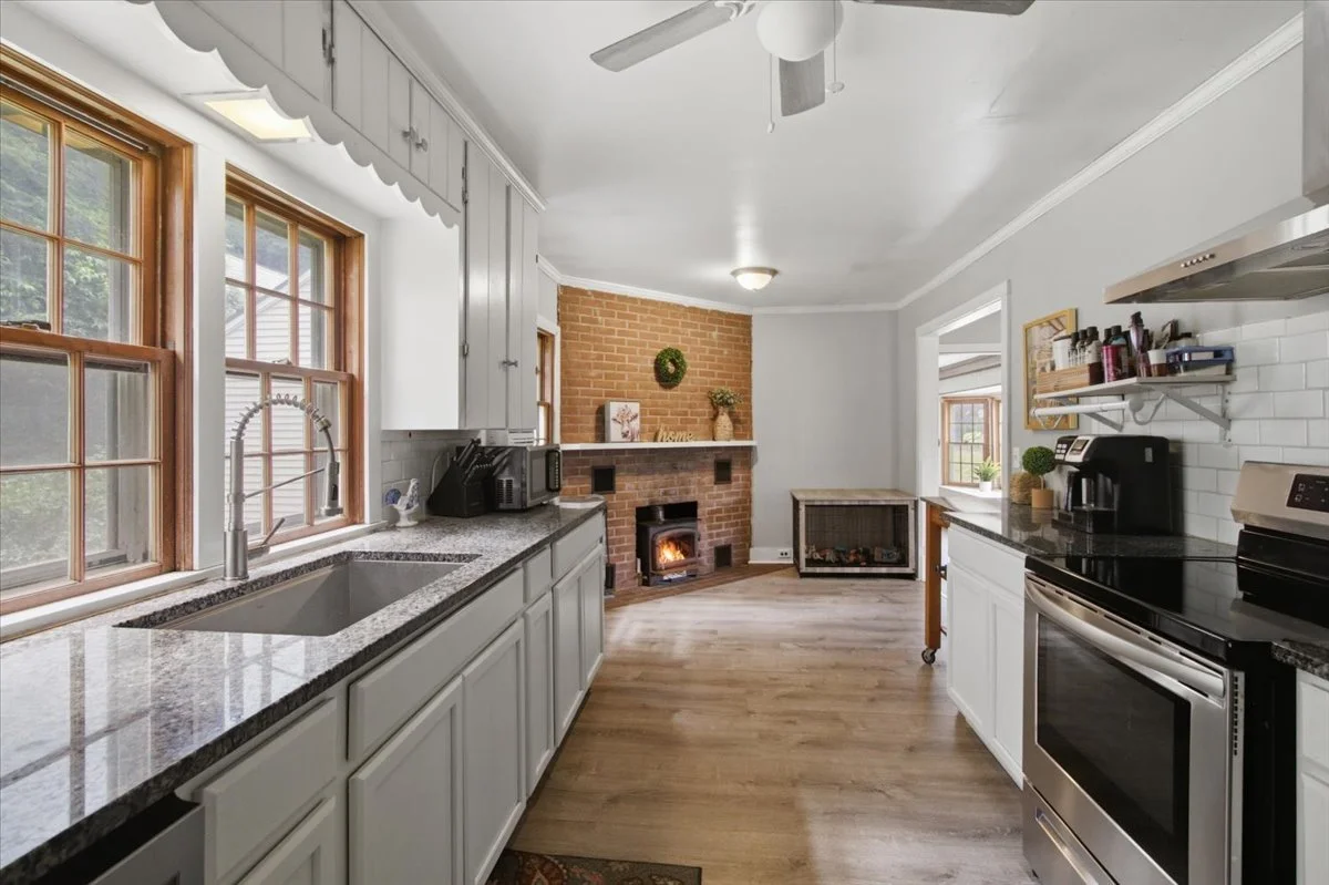 A sunny kitchen with large, modern appliances and sink, ceiling fan.