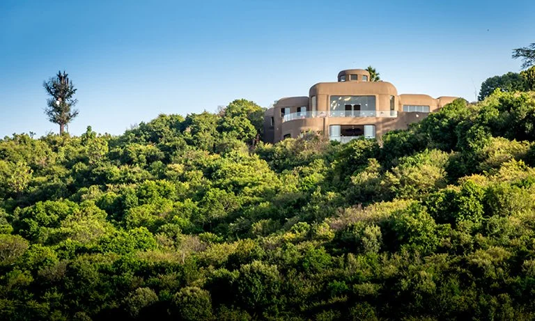 A villa on top of a tree covered hill