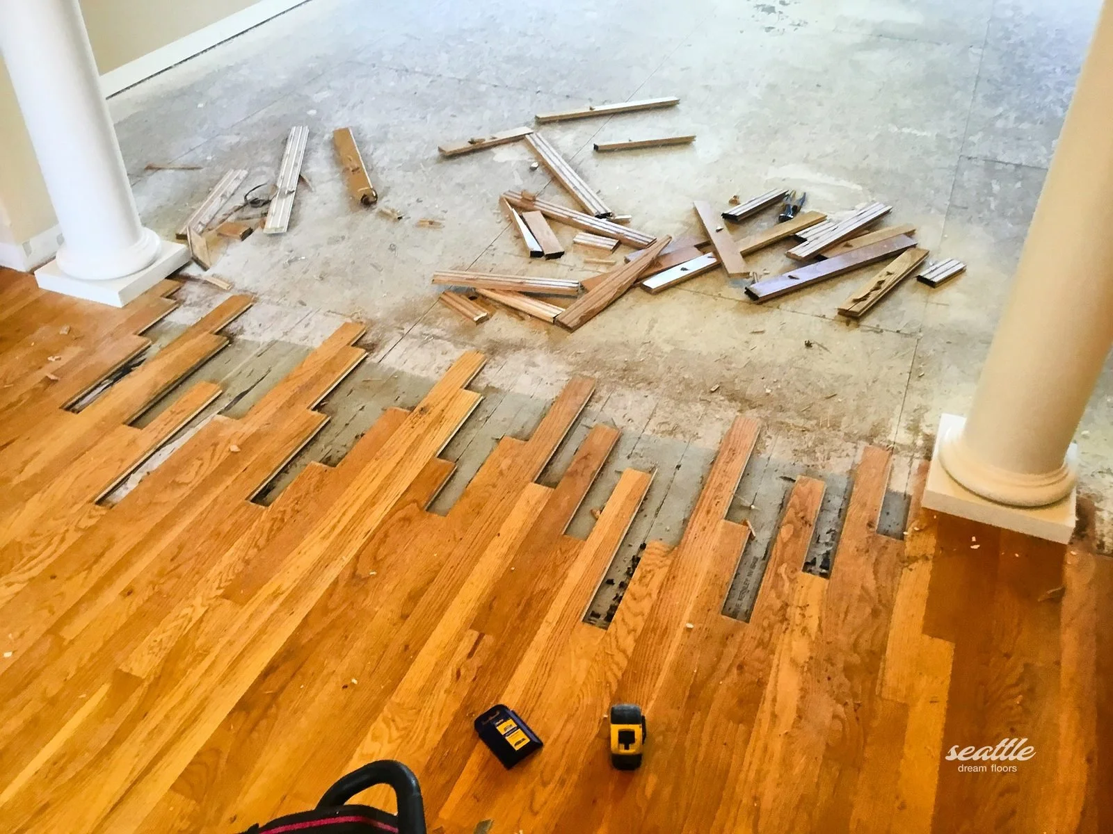 Amber floor cut back to a staggered edge with removed boards piled on bare subfloor