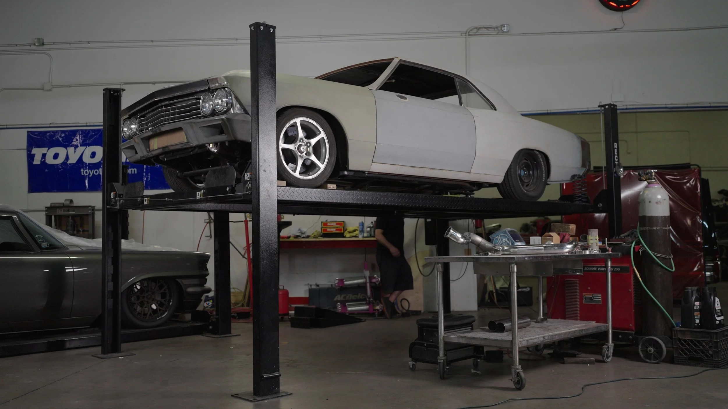 Classic muscle car on lift inside All American Hot Rods Phoenix workshop during Barrett-Jackson Cup competition preparation