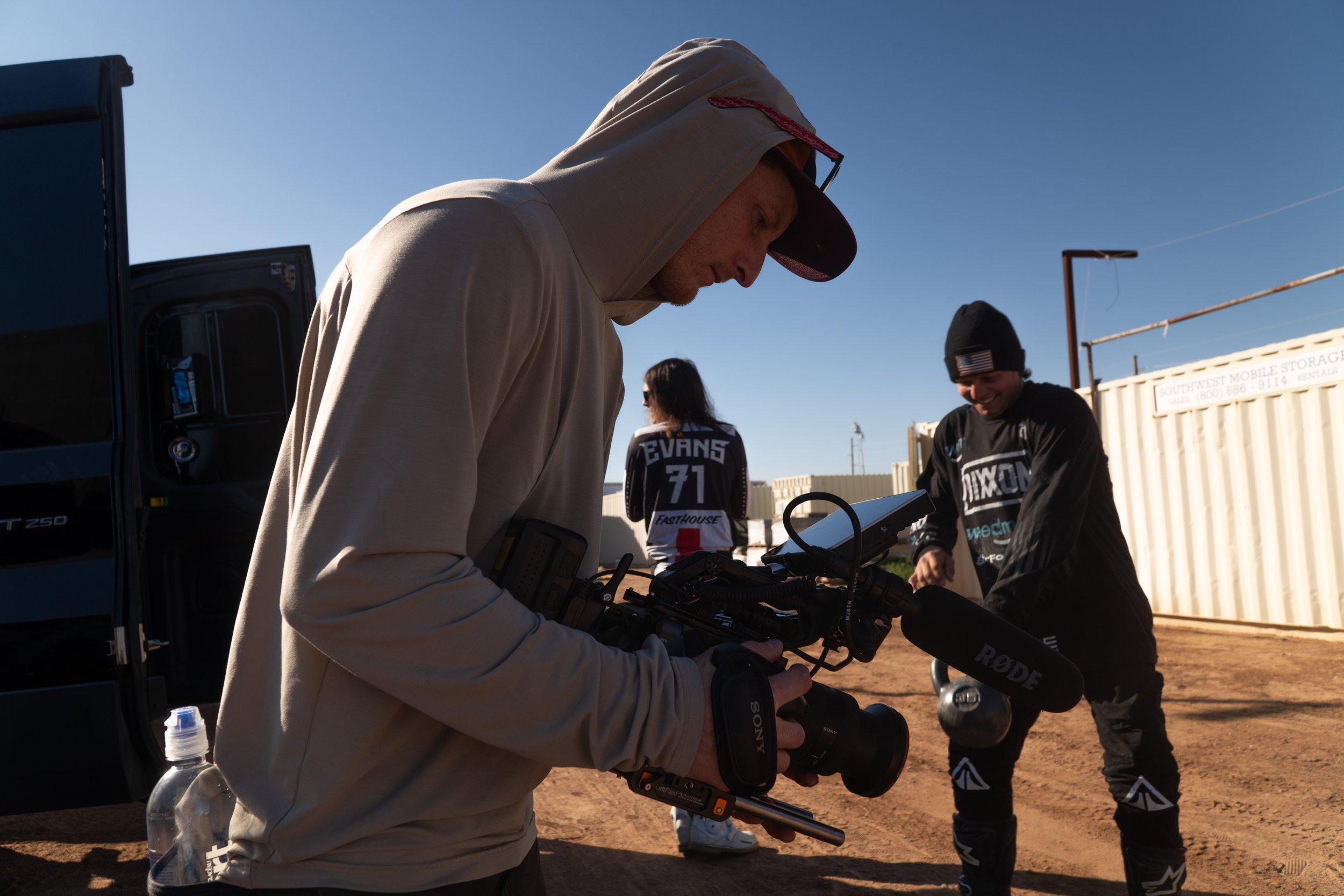 Camera operator preparing handheld rig during outdoor extreme sports production