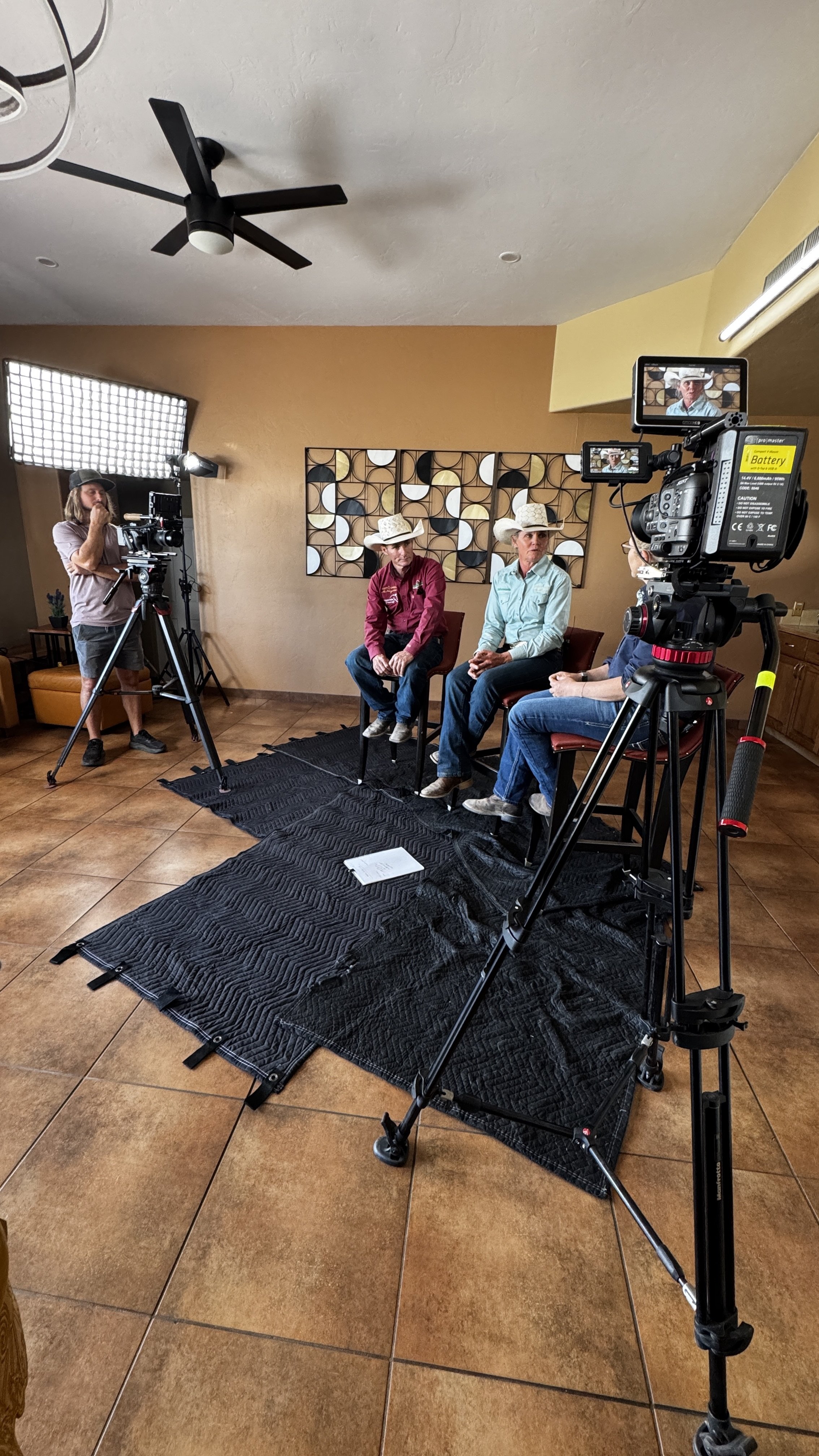 Documentary filmmaker recording an interview with ranchers using professional cinema cameras and lighting during a documentary production.