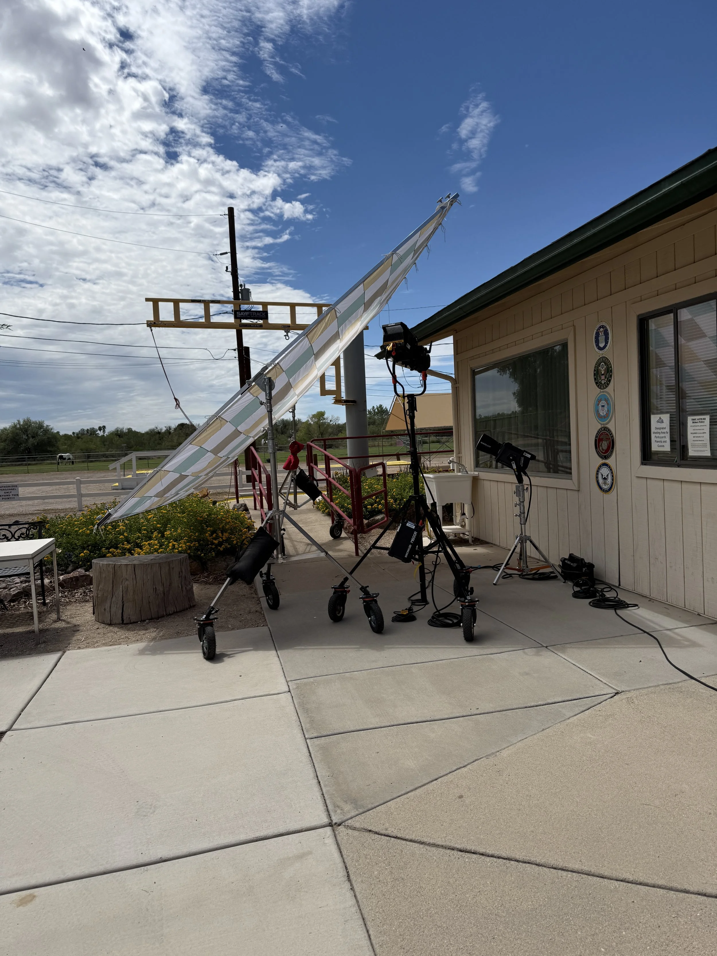 Documentary film crew setting up lighting and camera equipment outside an Arizona ranch location for an interview shoot.