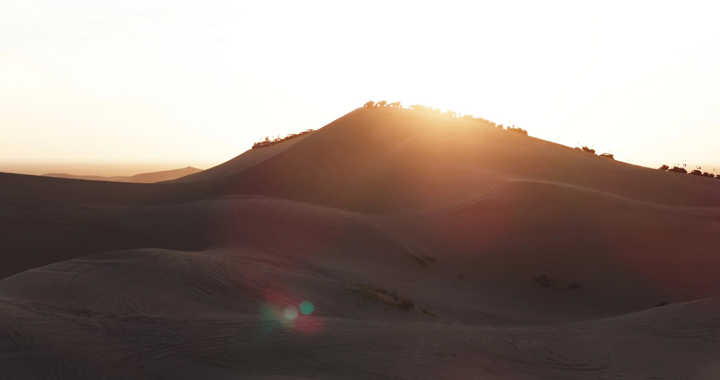 Sunset over desert sand dunes during the guys trip adventure.