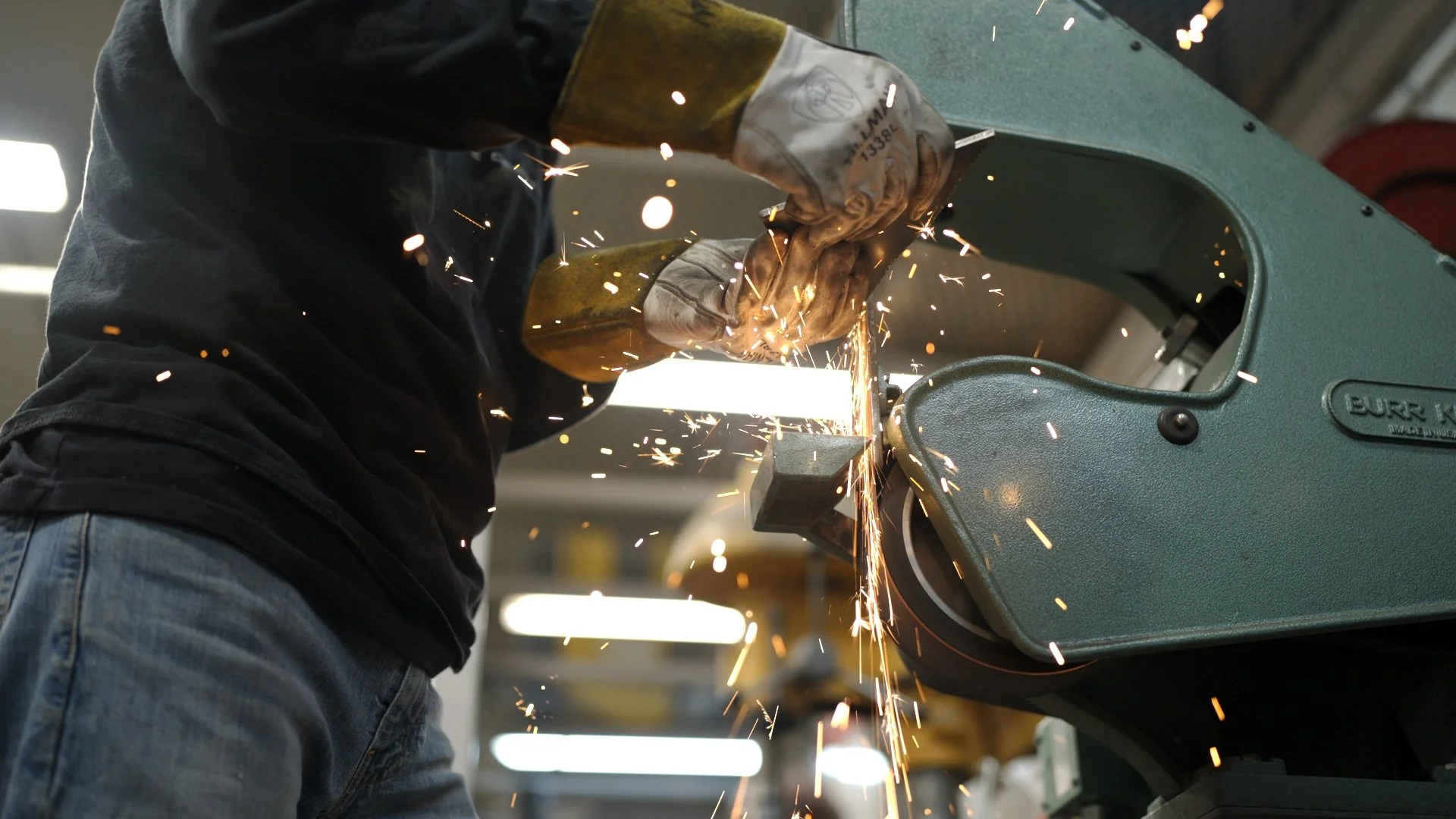 Automotive fabricator grinding metal with sparks flying while preparing a custom build for the Barrett-Jackson Cup competition in Scottsdale, Arizona.