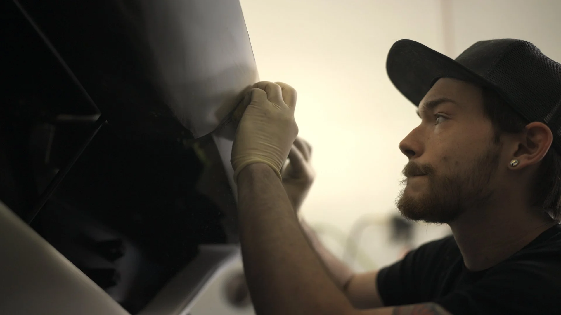 Car builder sanding body panel during Barrett-Jackson Cup competition build process.