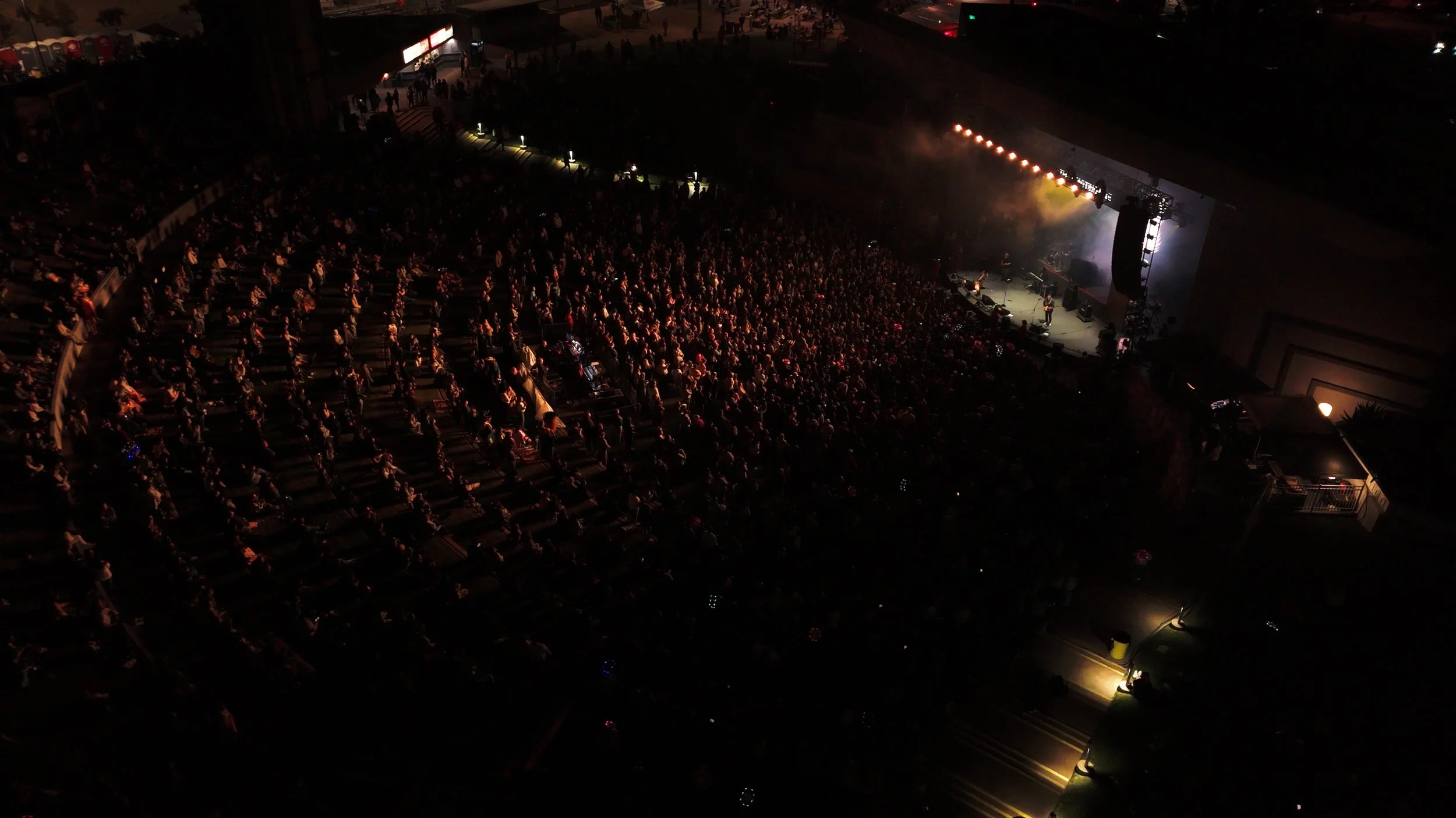 Large crowd at live event filmed from above capturing audience and stage lighting