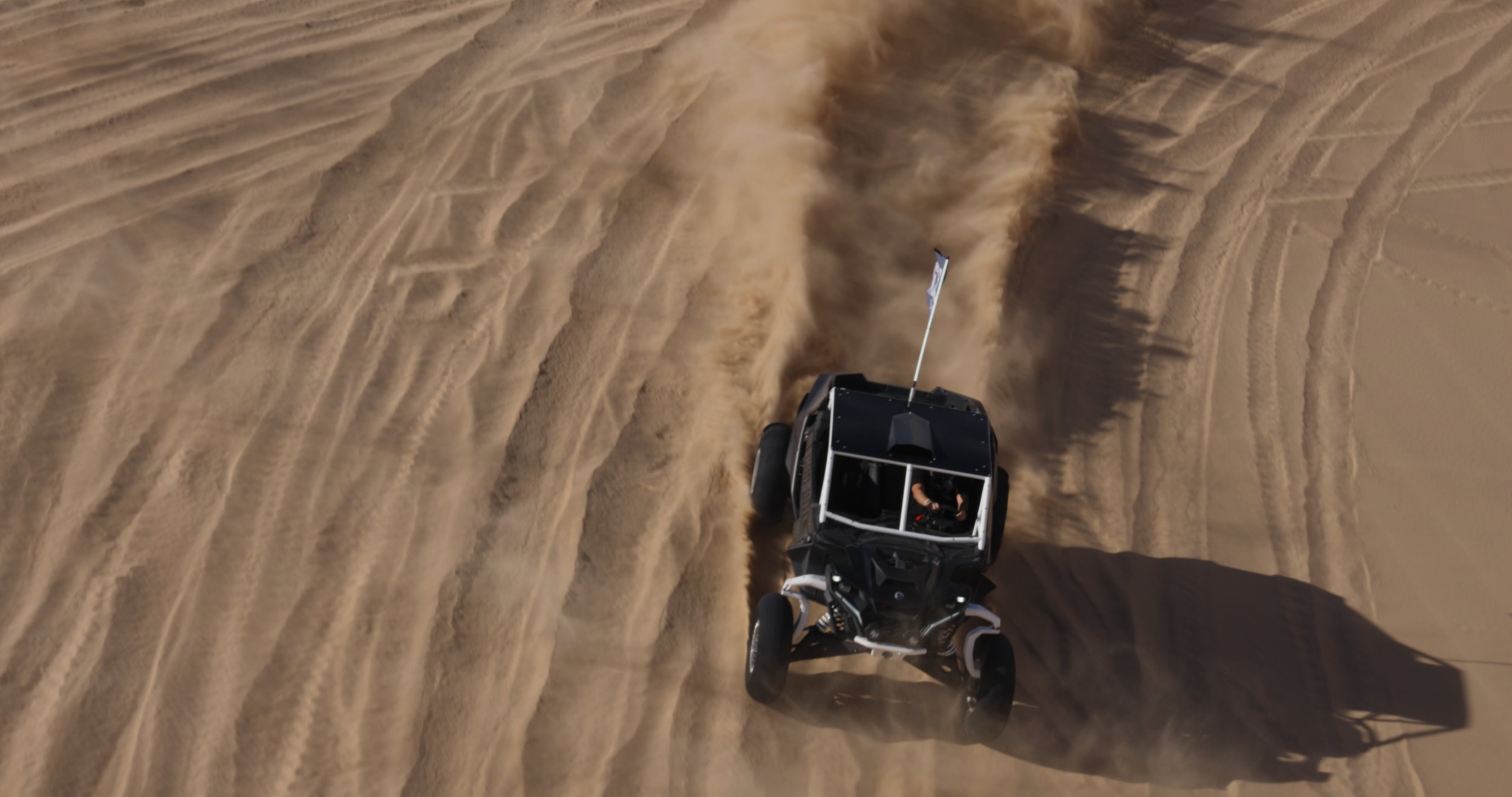 Aerial view of a UTV driving across desert sand dunes during a cinematic adventure trip.