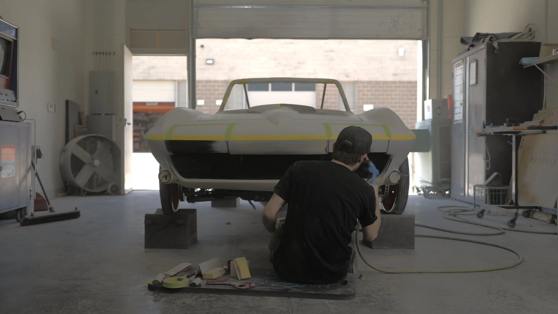 Custom car builder preparing a classic vehicle inside a fabrication shop for a competition-based automotive documentary series.