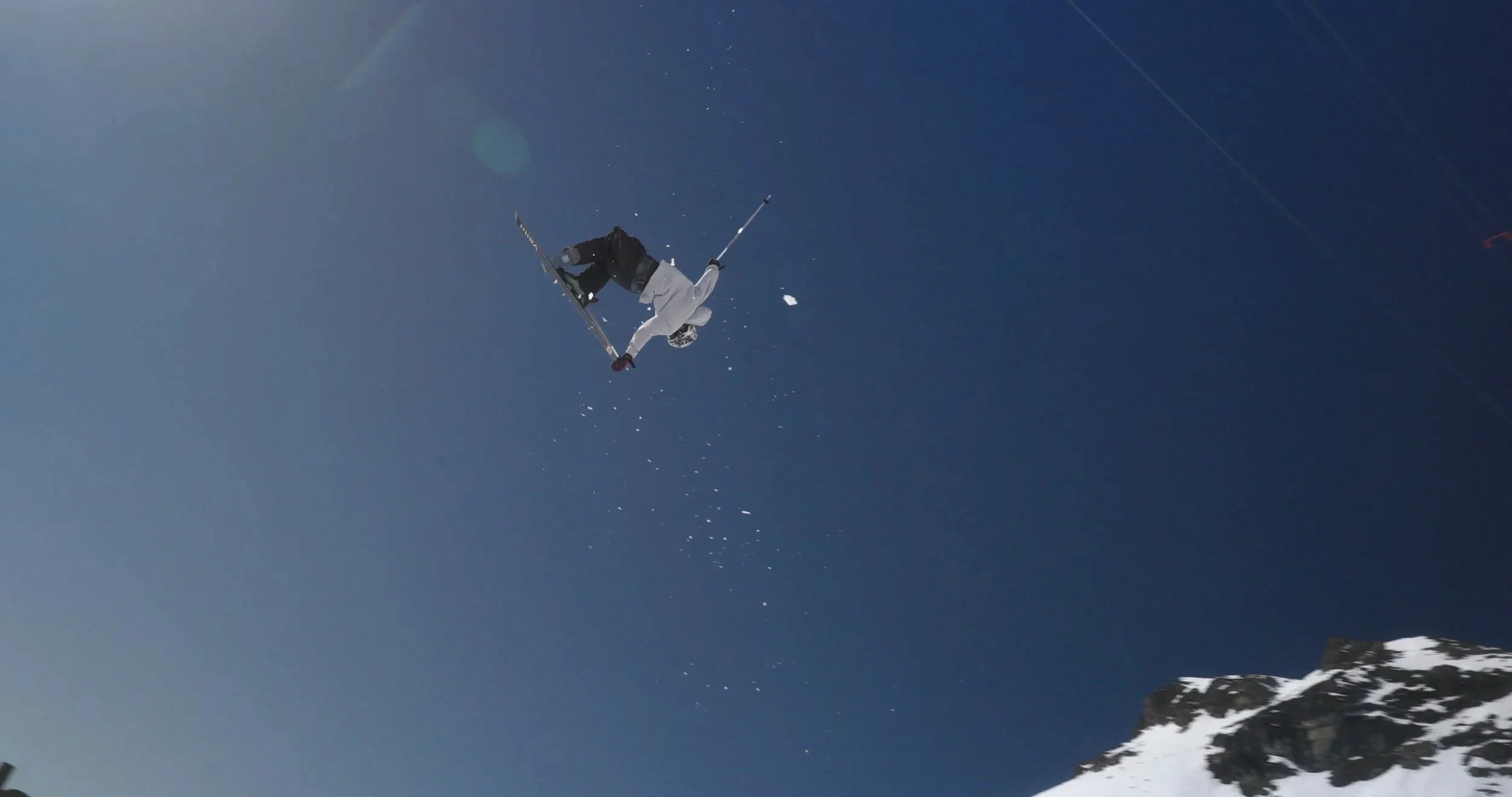 Professional freeski athlete launching off massive snow feature in Switzerland during Swatch Nines, documented for extreme sports cinematography and documentary production.