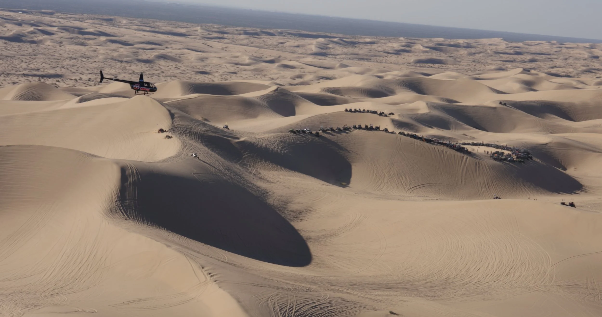Wide aerial landscape of desert sand dunes explored during the adventure documentary trip.
