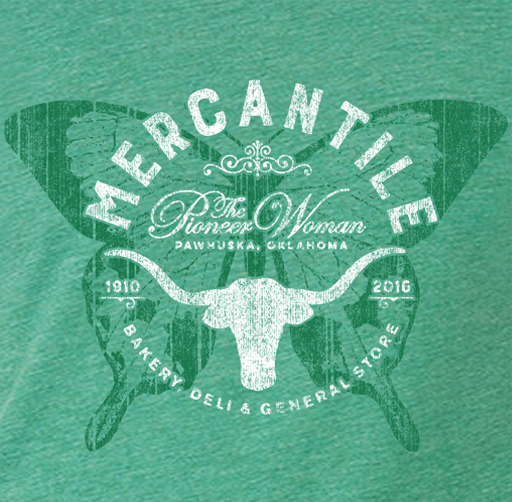 Apparel design for Pioneer Woman, vintage-style graphic featuring a butterfly with a longhorn skull in the center, text reading "Mercantile, The Thirsty Woman, Pawhuska, Oklahoma," and dates 1916 and 2016, indicating a century span.
