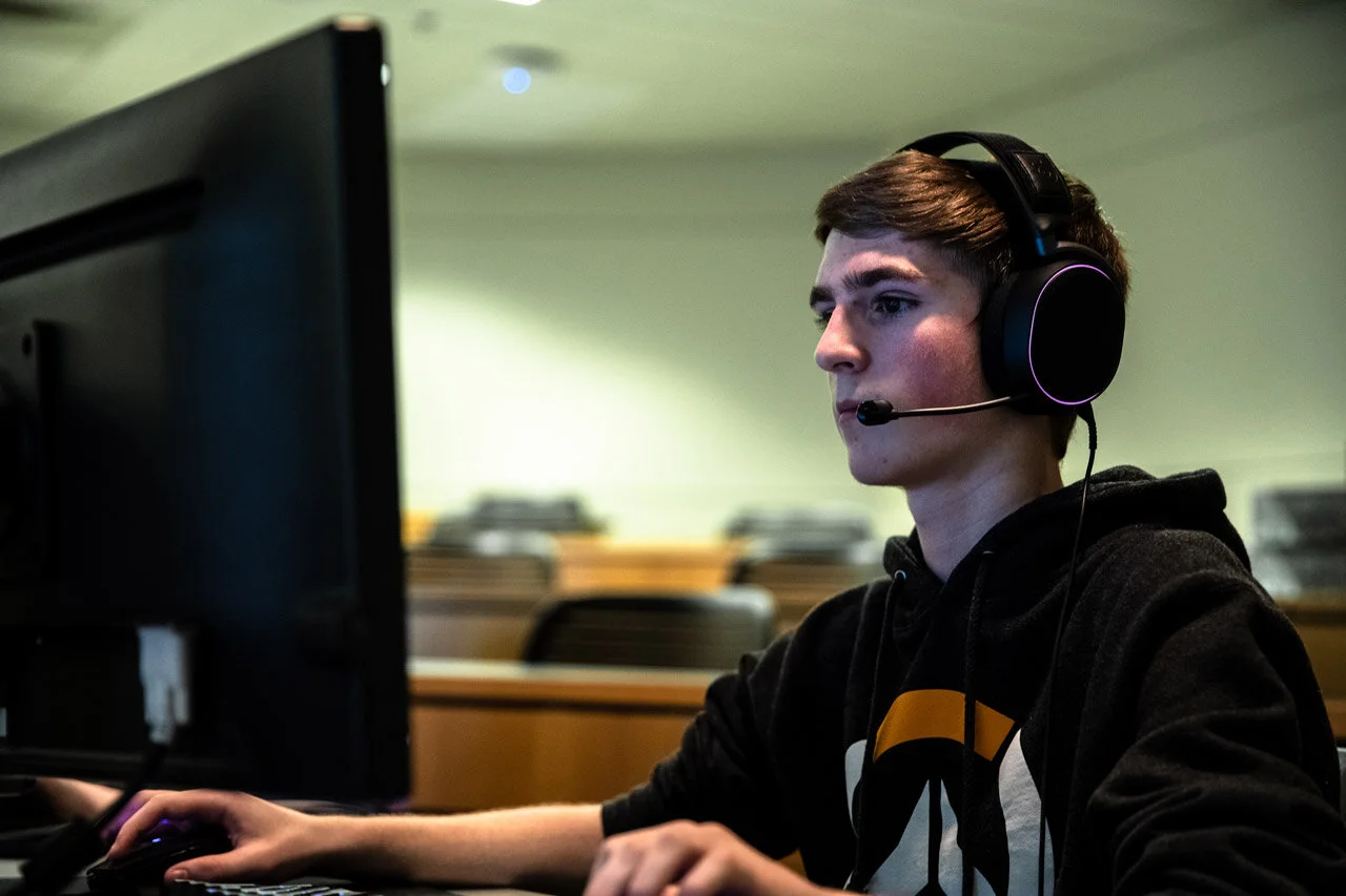 A young man engaged in esports, sporting a headset as he concentrates on his match.