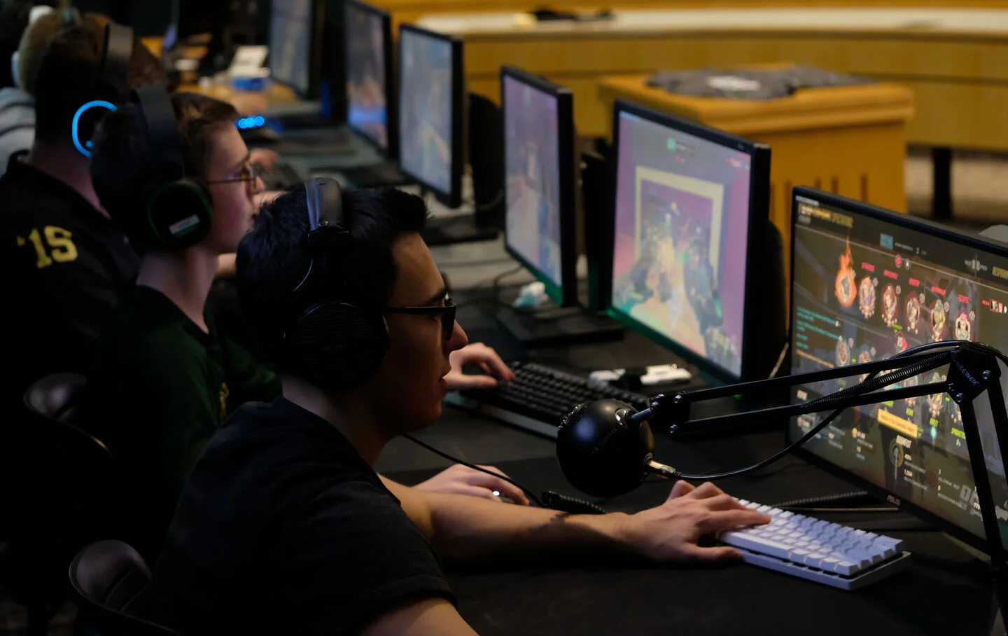 A diverse group of individuals engaged in competitive gaming on computer monitors, showcasing the excitement of esports.