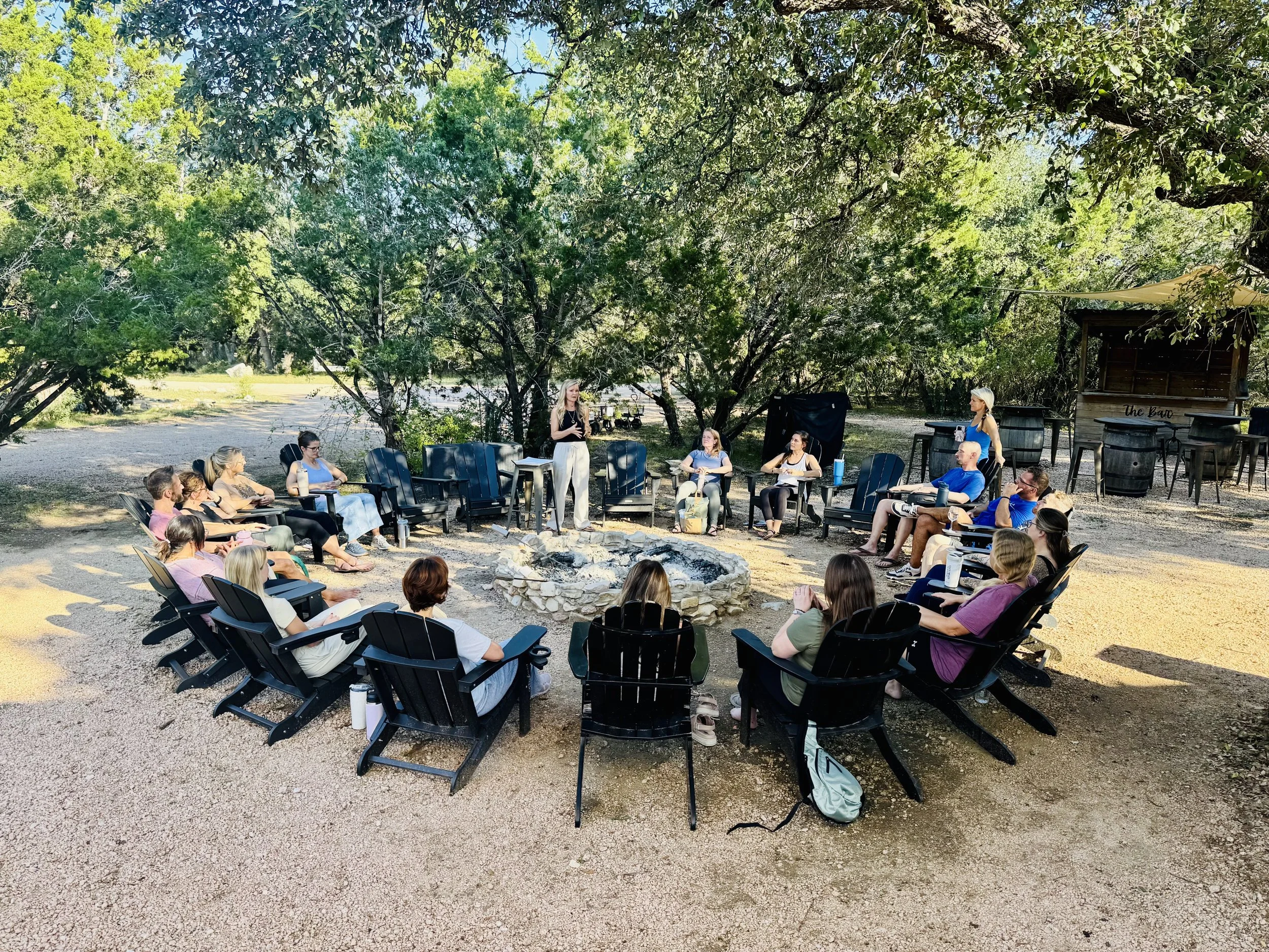 People in a group prayer or meditation circle, with eyes closed and hands on each other's shoulders.