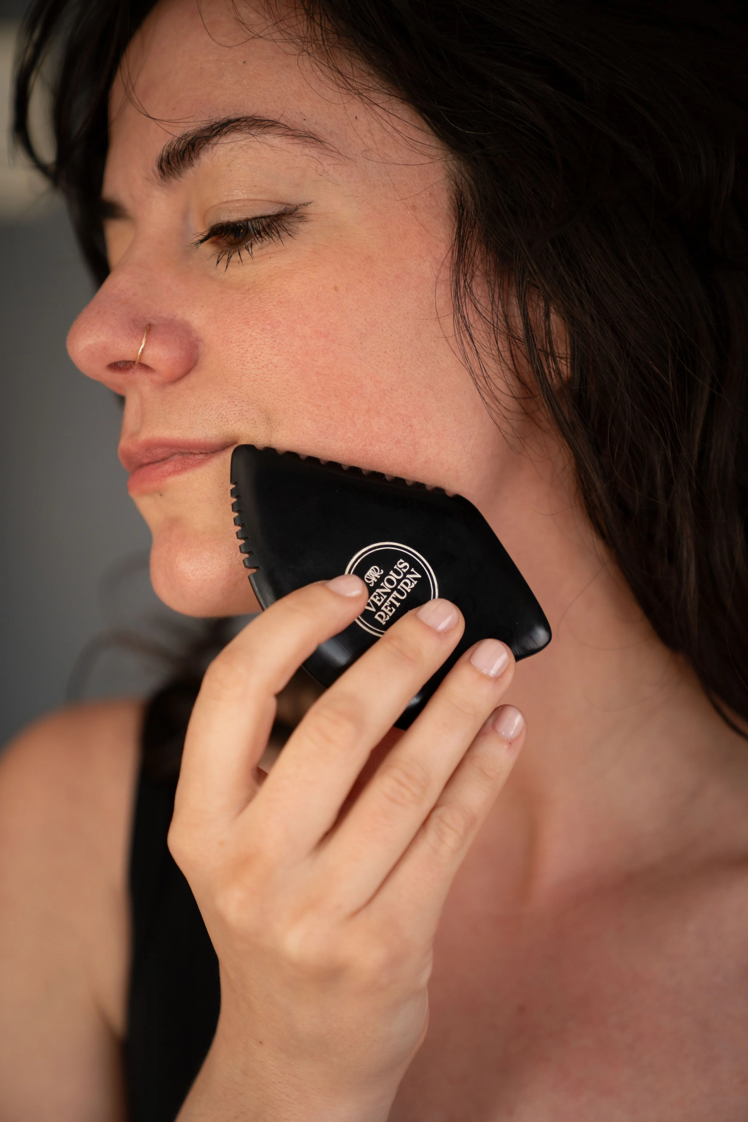 Venous Return Healing's Bian Gua Sha Stone for lymphatic drainage and self massage in use on the face of licensed massage therapist Lorna Skuraton.