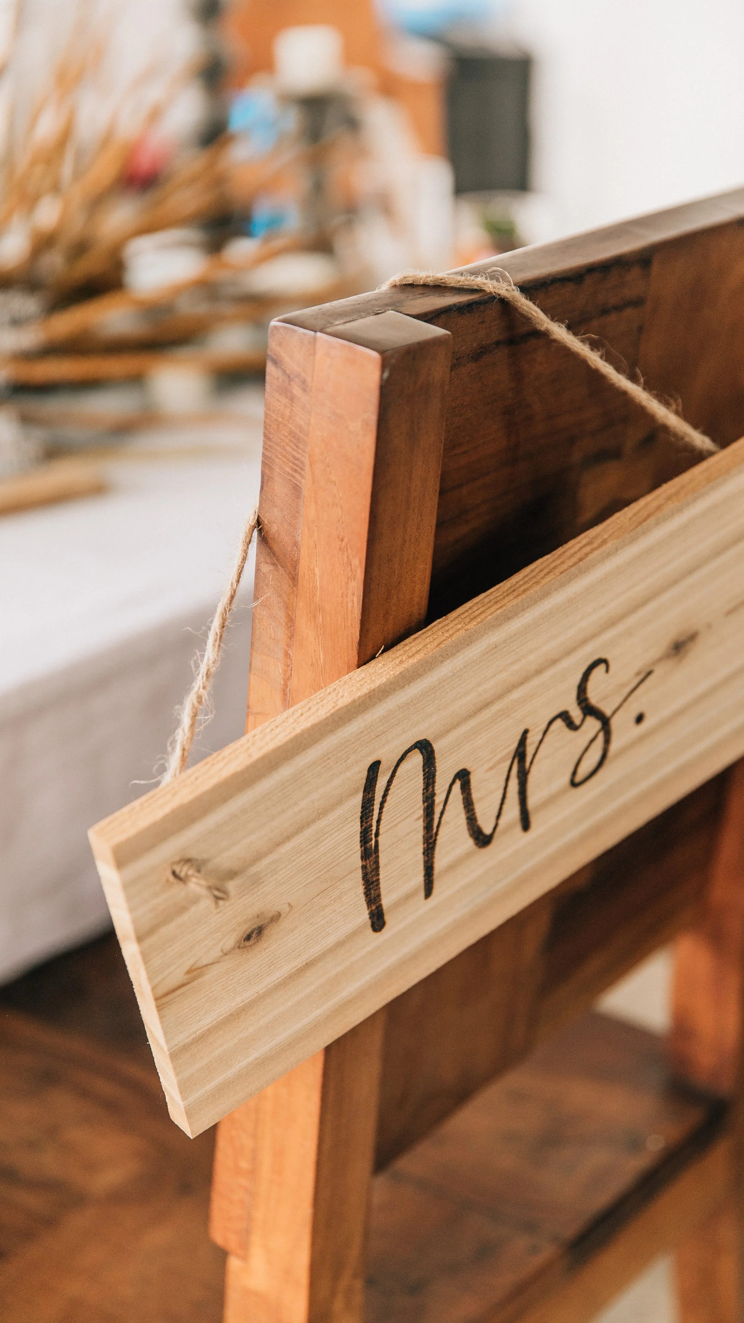Close-up of a chair at a wedding with a wooden sign with the word 'Mrs.' burned into the wood.