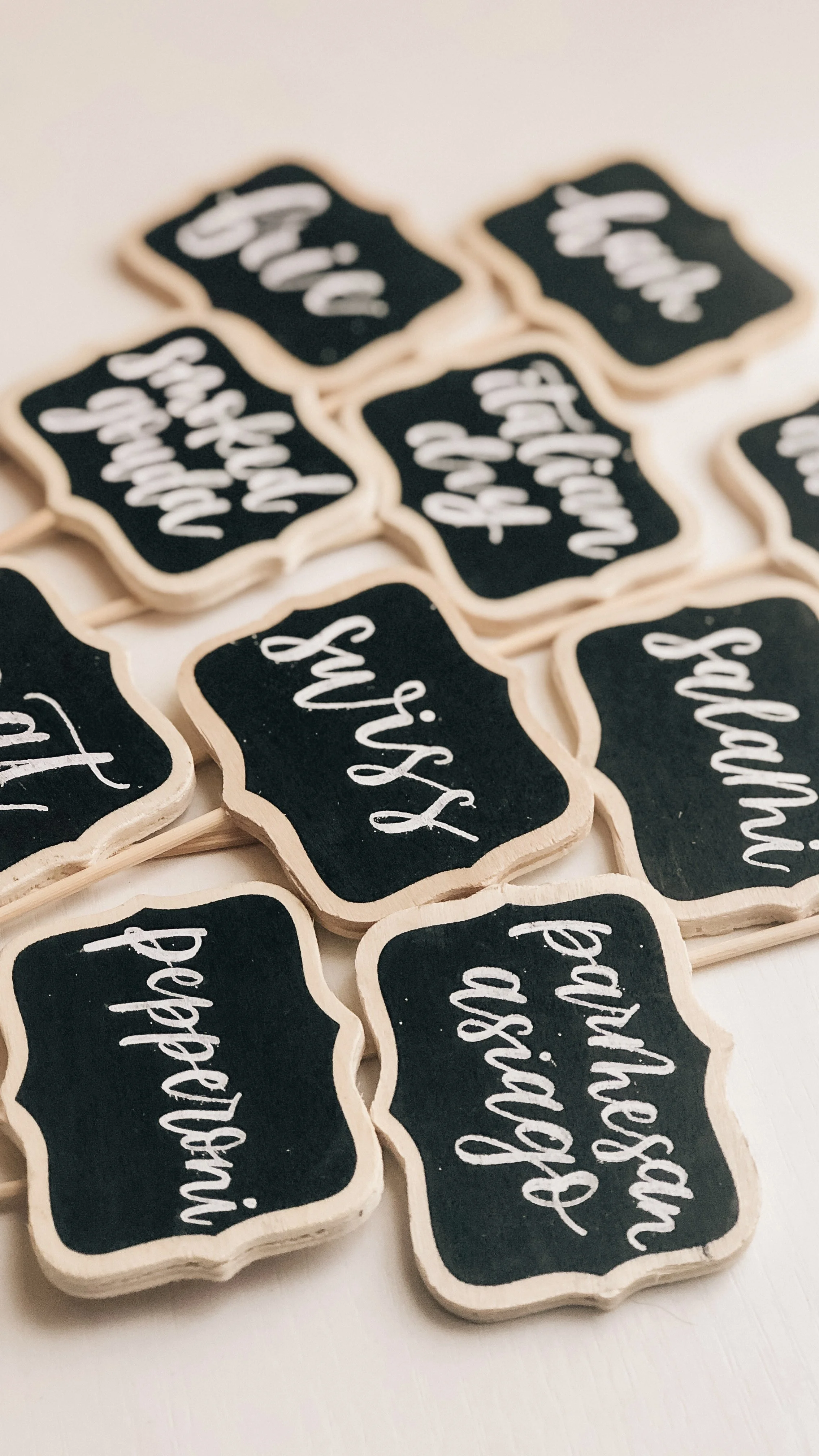 Multiple small characutrie chalkboard-style signs with white calligraphy writing on black backgrounds