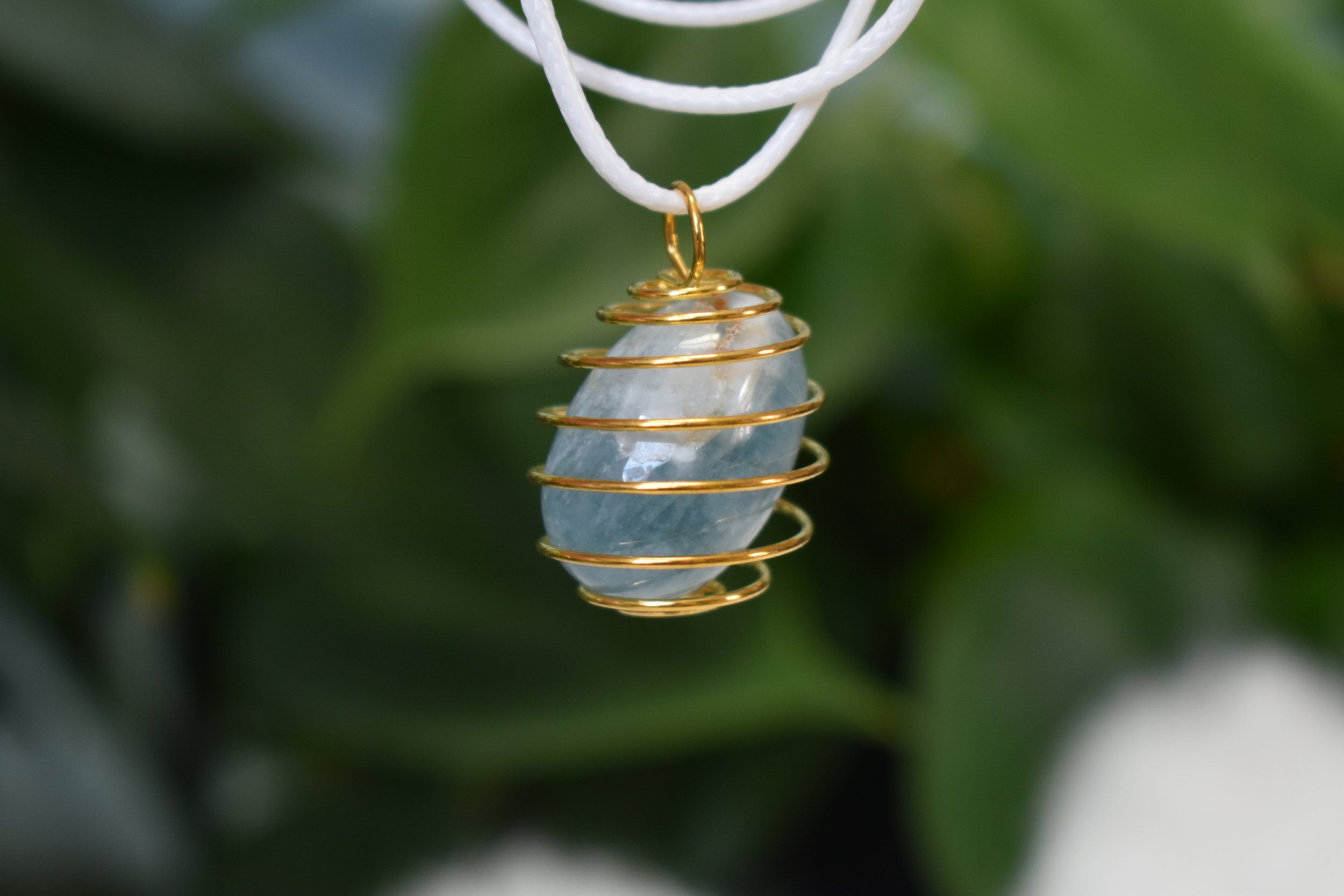 Aquamarine tumble cage with a white cord